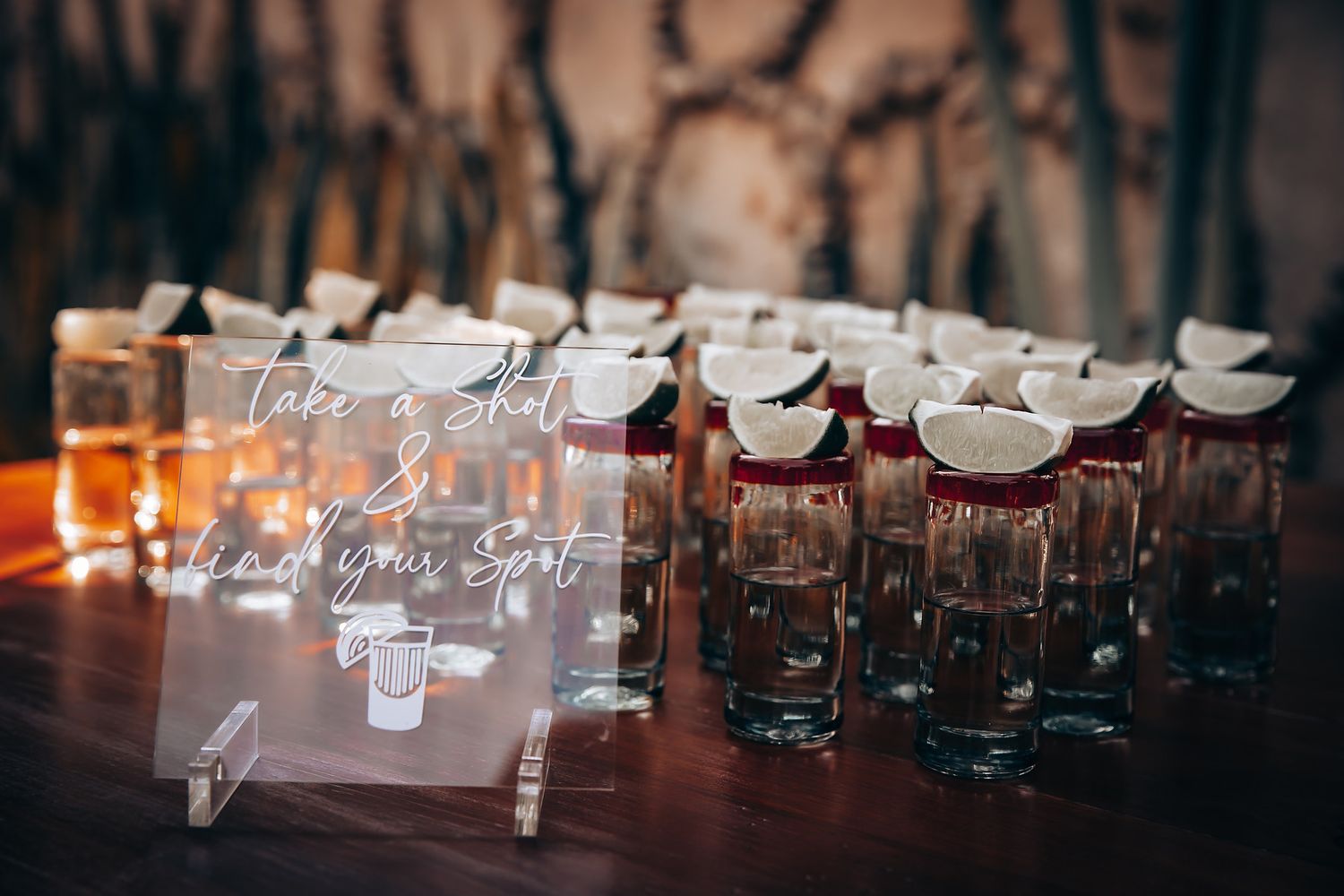 Row of elegant glass wedding place cards with calligraphy illuminated by warm lighting.