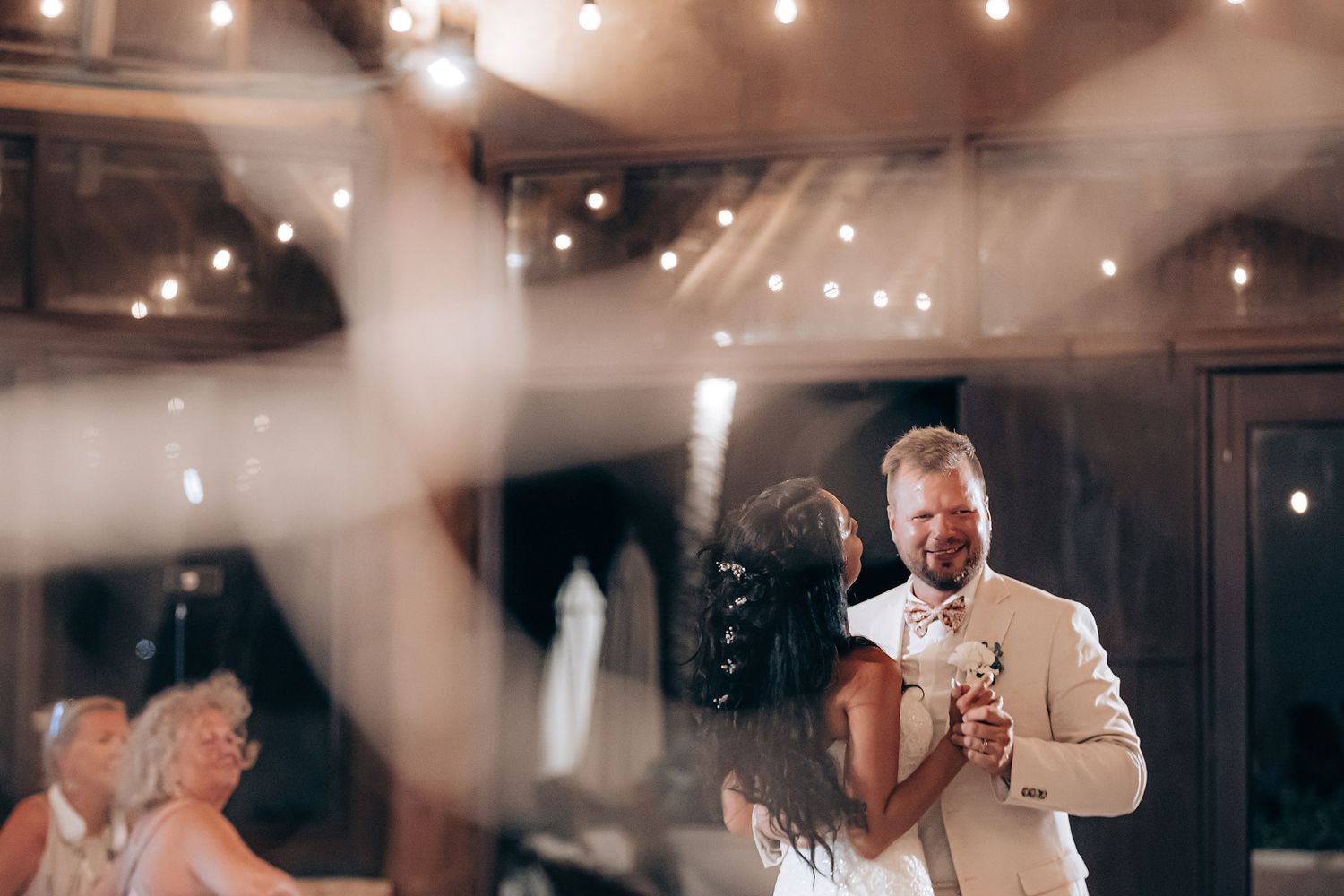 Wedding reception under string lights with guests dancing and celebrating.