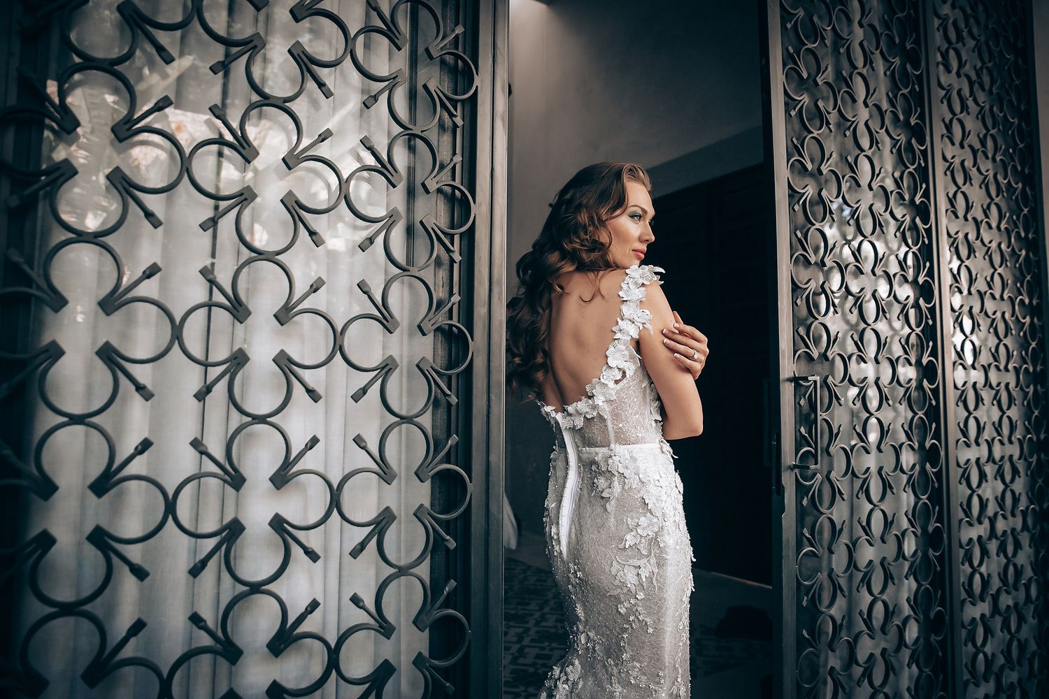 Bridal portraits against a patterned wall with dramatic lighting and lace details.