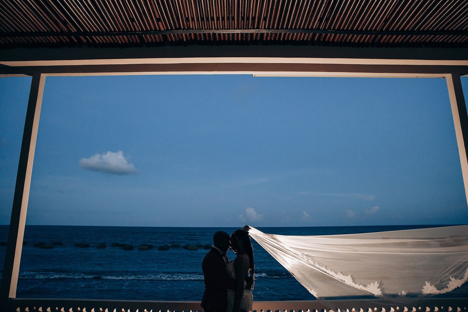 Series of beach wedding photos with flowing white veil against ocean backdrop and blue skies.