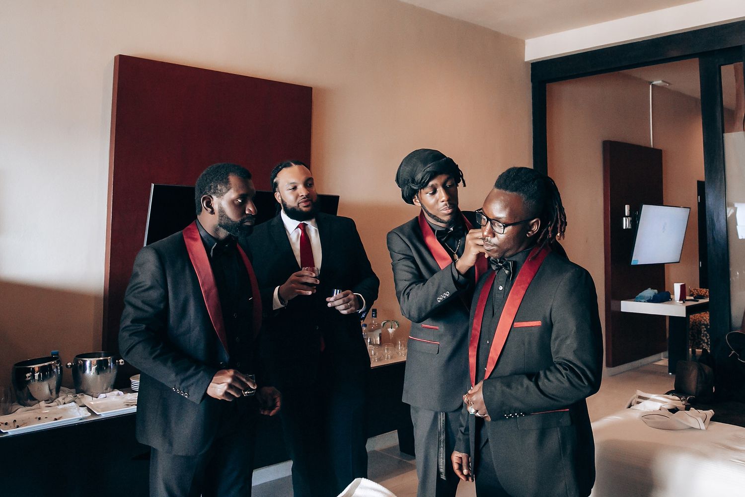 A group of wedding guests in formal attire gather and socialize during a celebration.