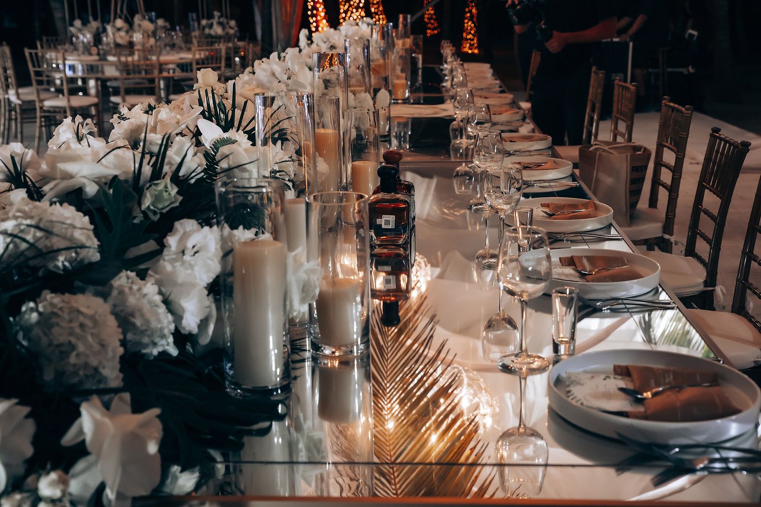 An elegant wedding reception table setting with tall candles, white flowers and crystal glassware.