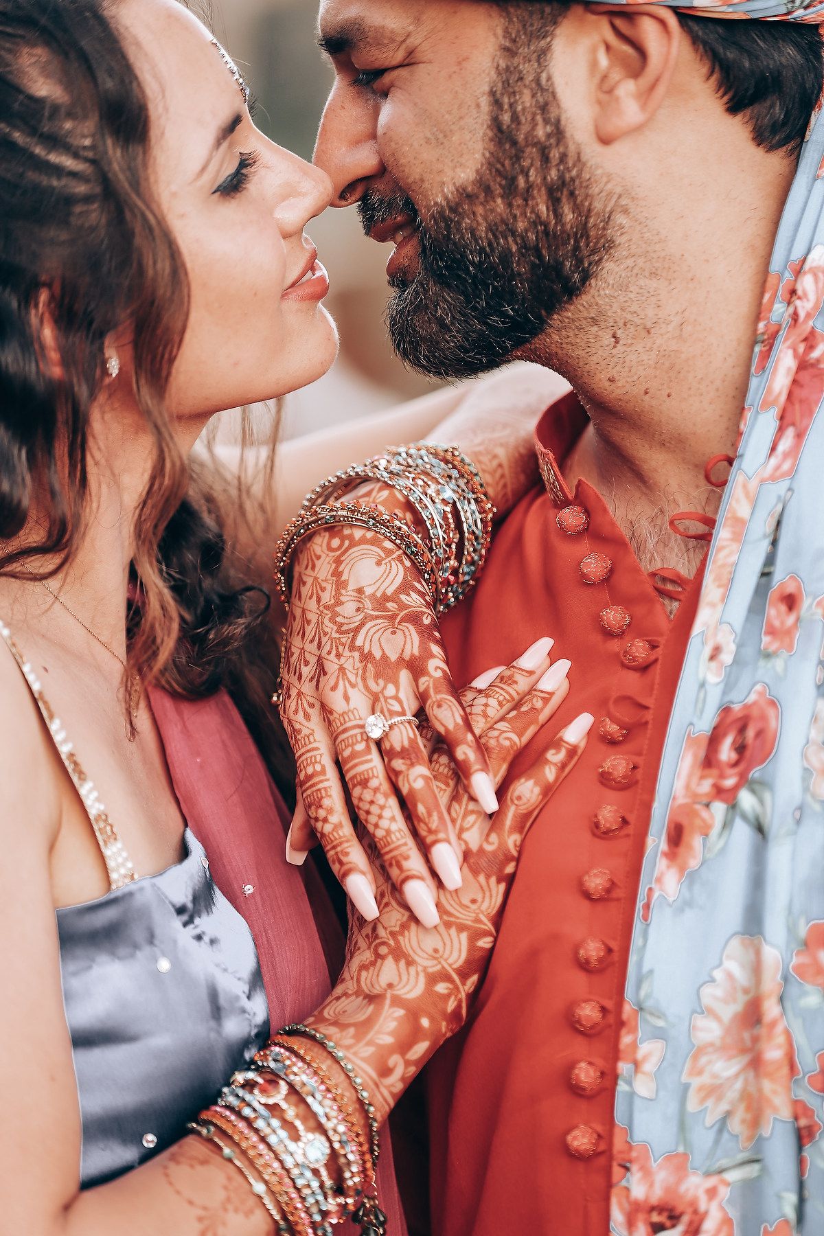Romantic couple sharing intimate moments in traditional Indian wedding attire with intricate henna designs.