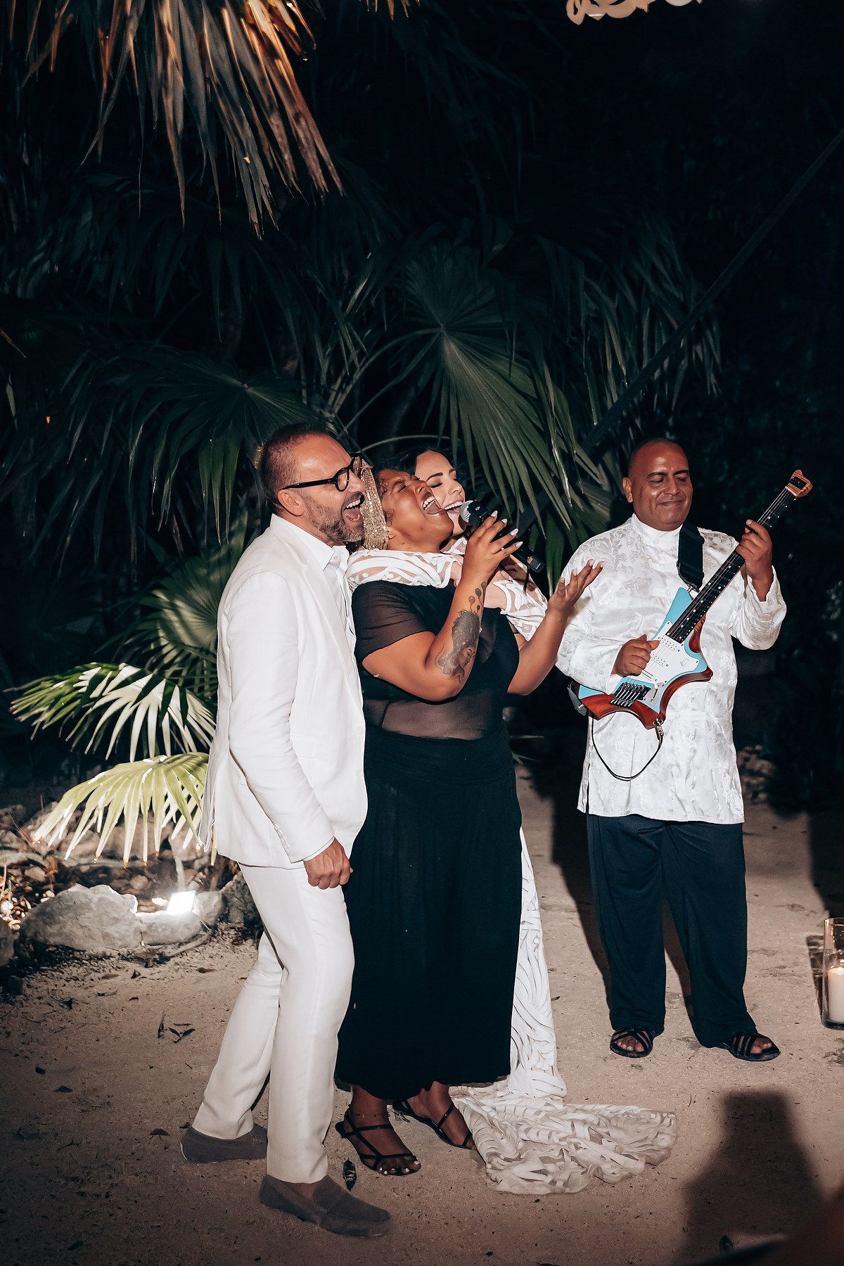 People dancing at a nighttime beach party wearing black and white formal attire.
