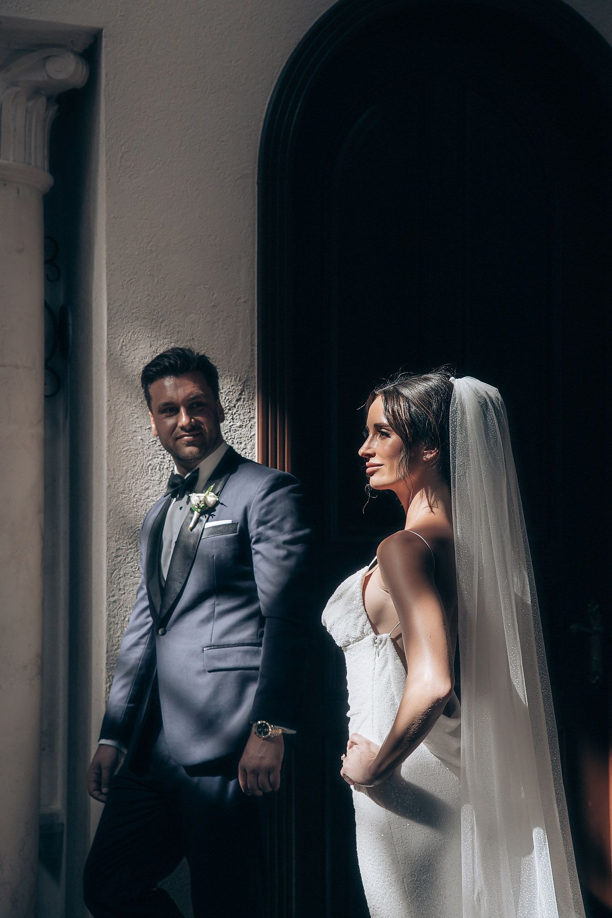 A bride and groom share intimate moments in a series of black and white wedding portraits against an arched doorway.