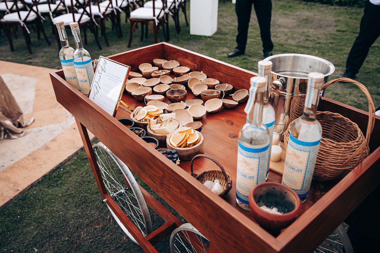 Rustic wooden cart displaying cookies and beverages for an outdoor event service setup.