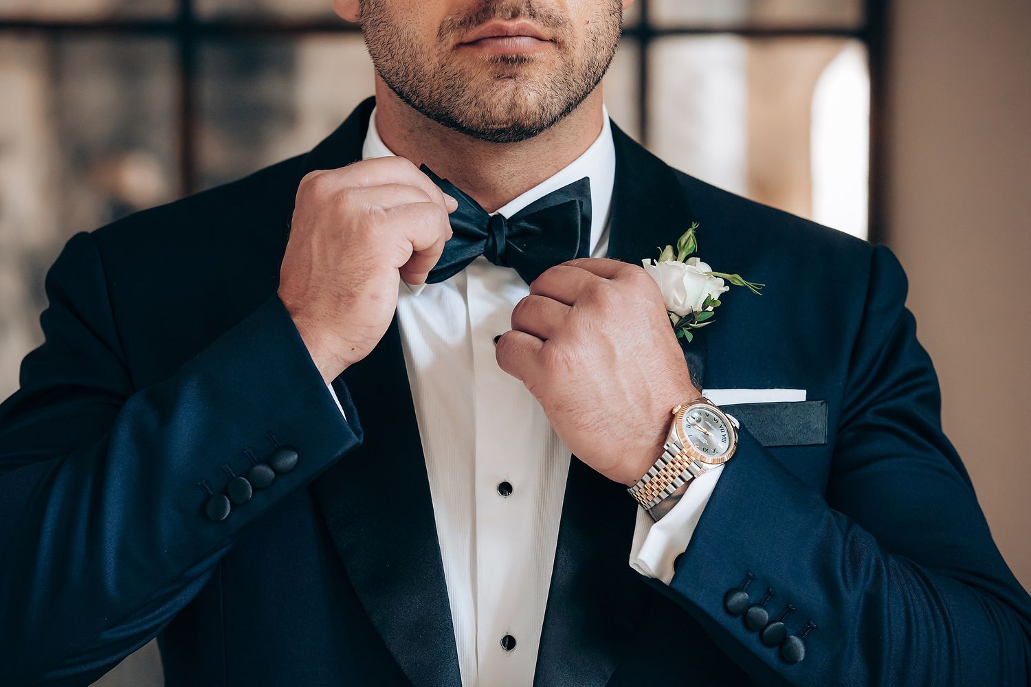 Close up details of a formal black tuxedo with white shirt and bow tie at a wedding event.