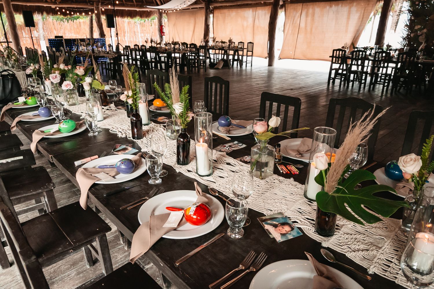Elegantly set reception tables with dark wood chairs, floral centerpieces, and place settings under a covered venue.