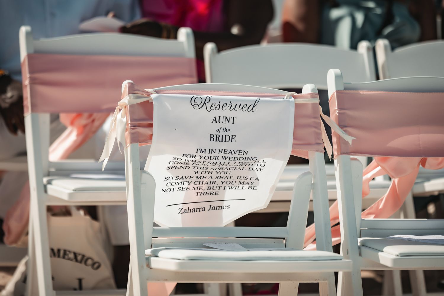 Reserved white chair sign for the bride's aunt in heaven at an outdoor wedding ceremony in Mexico.