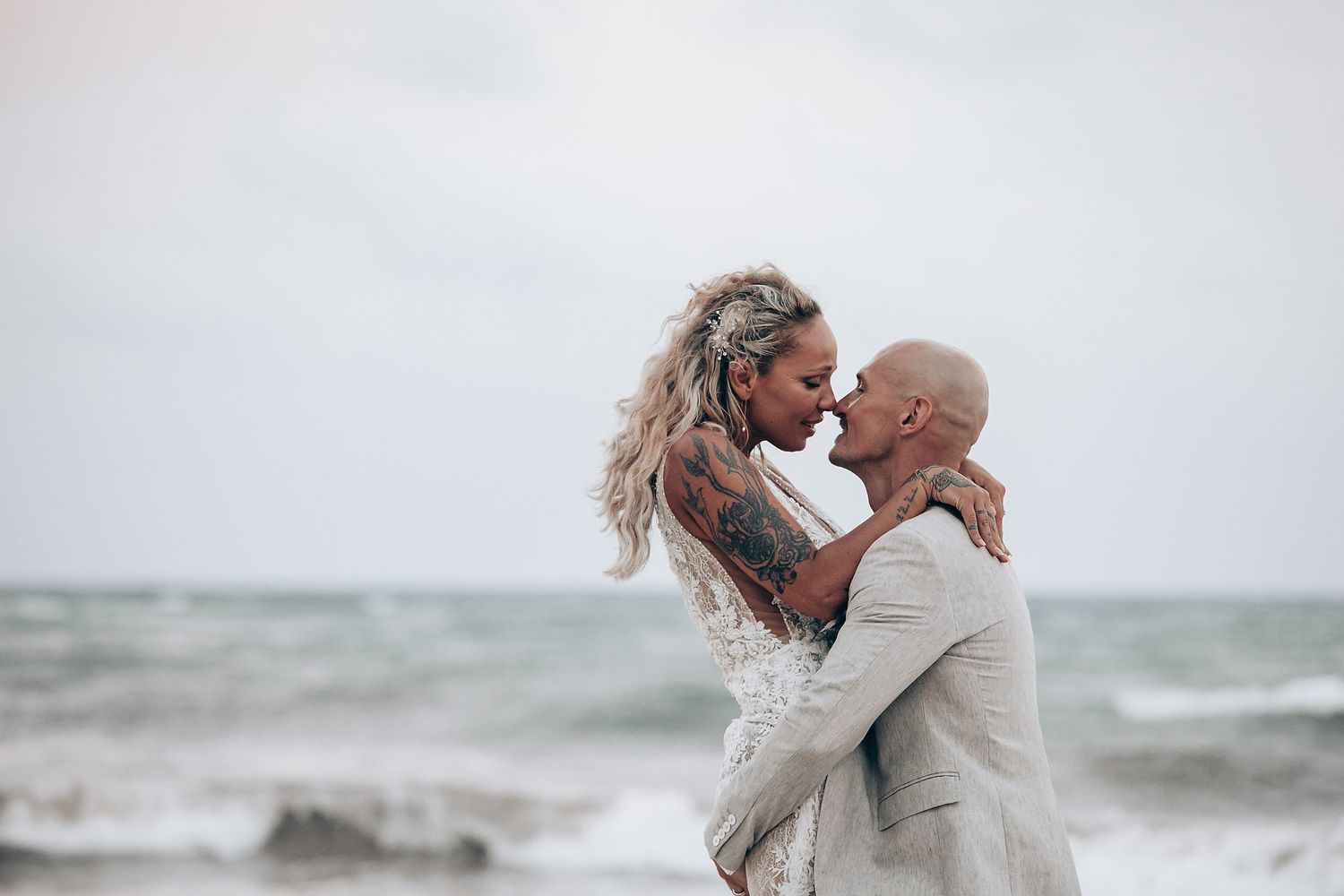 A joyful wedding moment captured on a cloudy beach.
