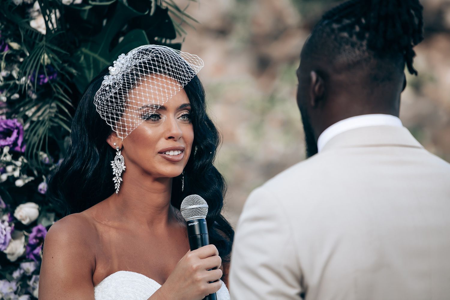 Wedding ceremony moment with microphone and floral decorations in natural setting.