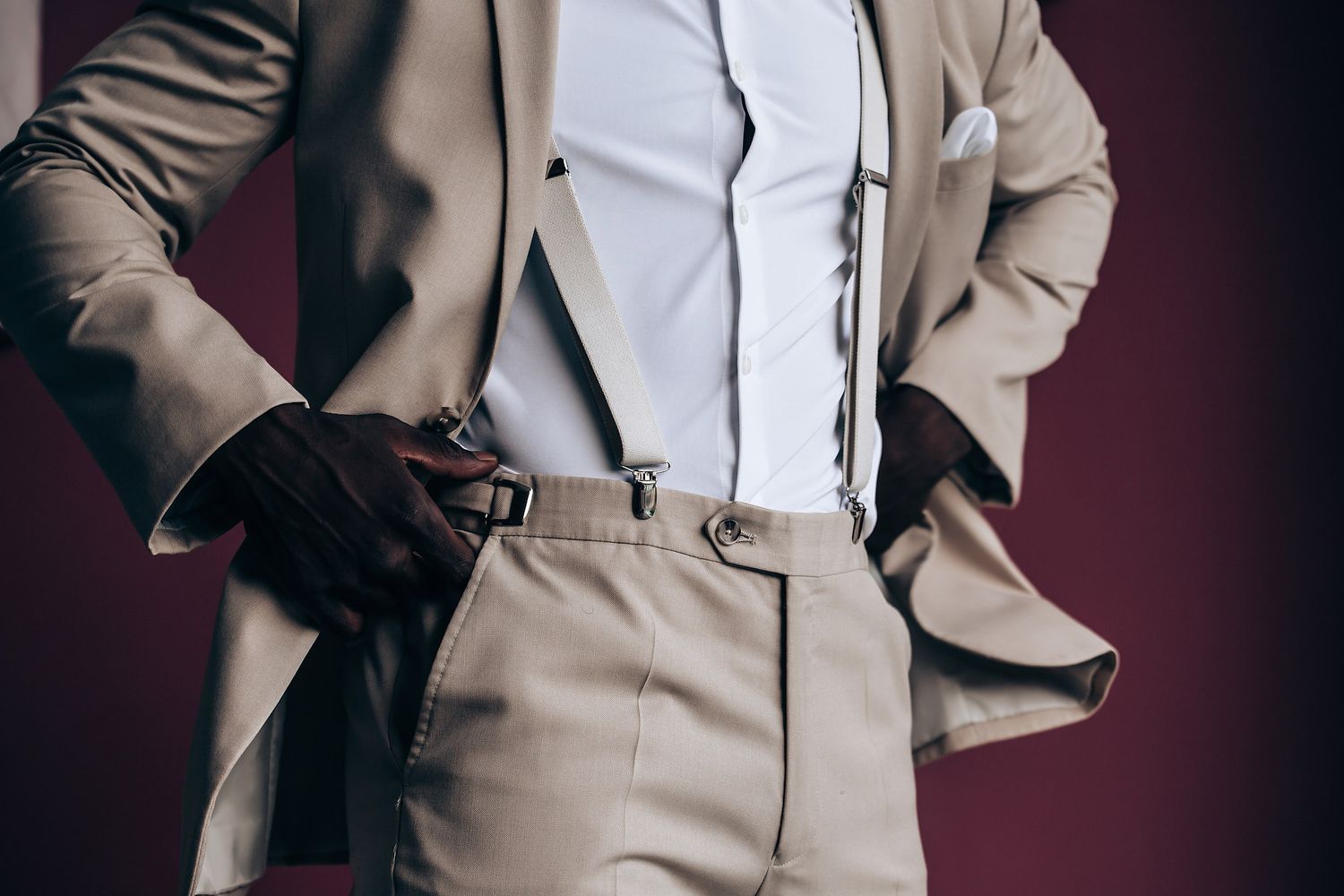 A person in a light beige suit adjusts their tie while getting ready.