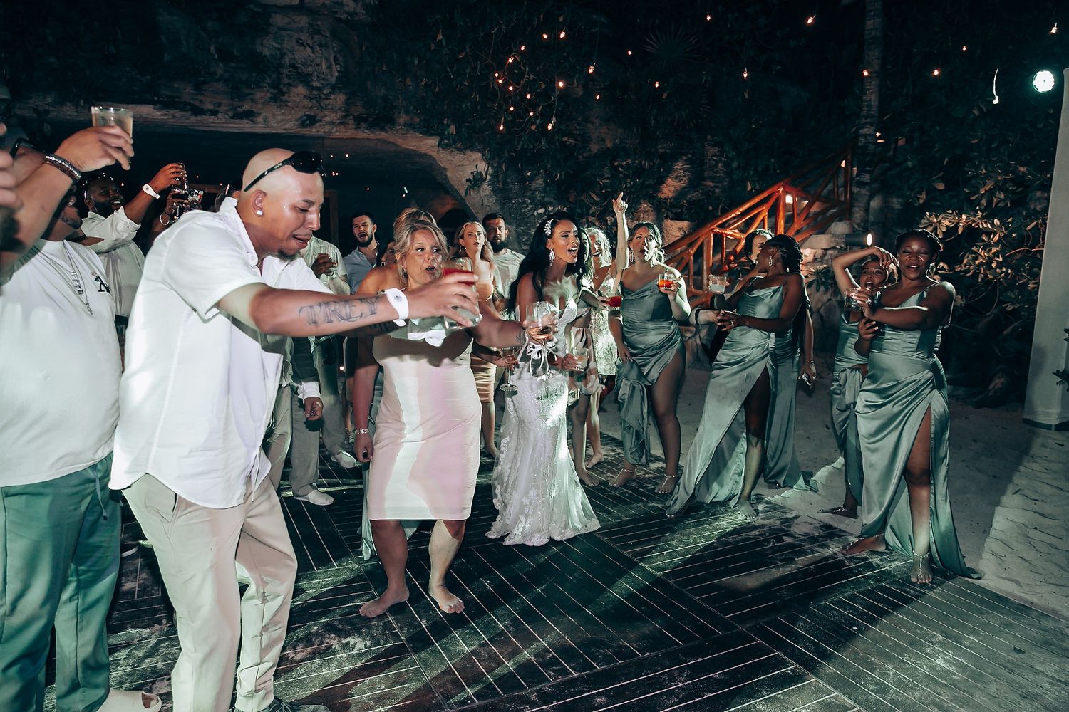 Large crowd of wedding guests gathered on a dance floor during a nighttime celebration.