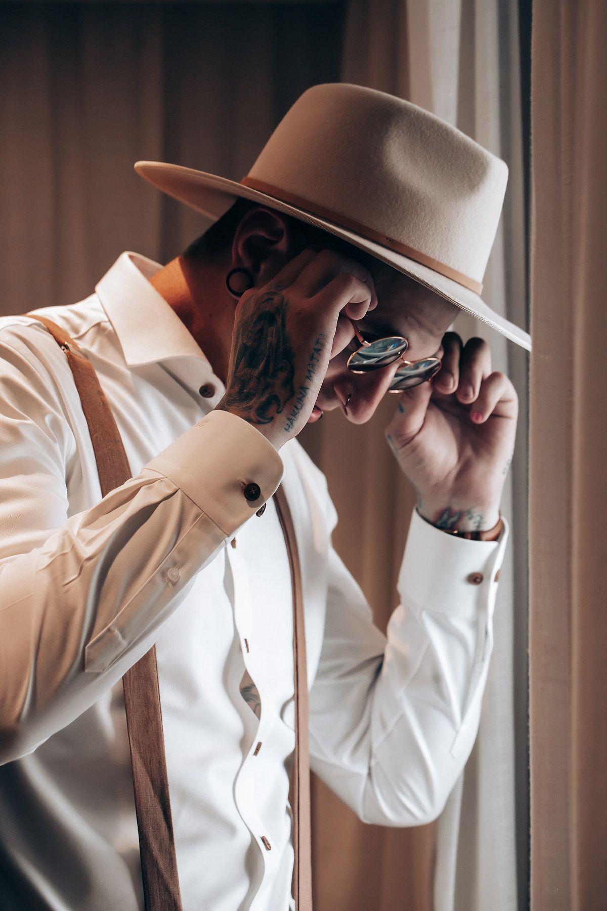 A series of close-up shots showing a person in a white suit and hat adjusting their collar and tie.