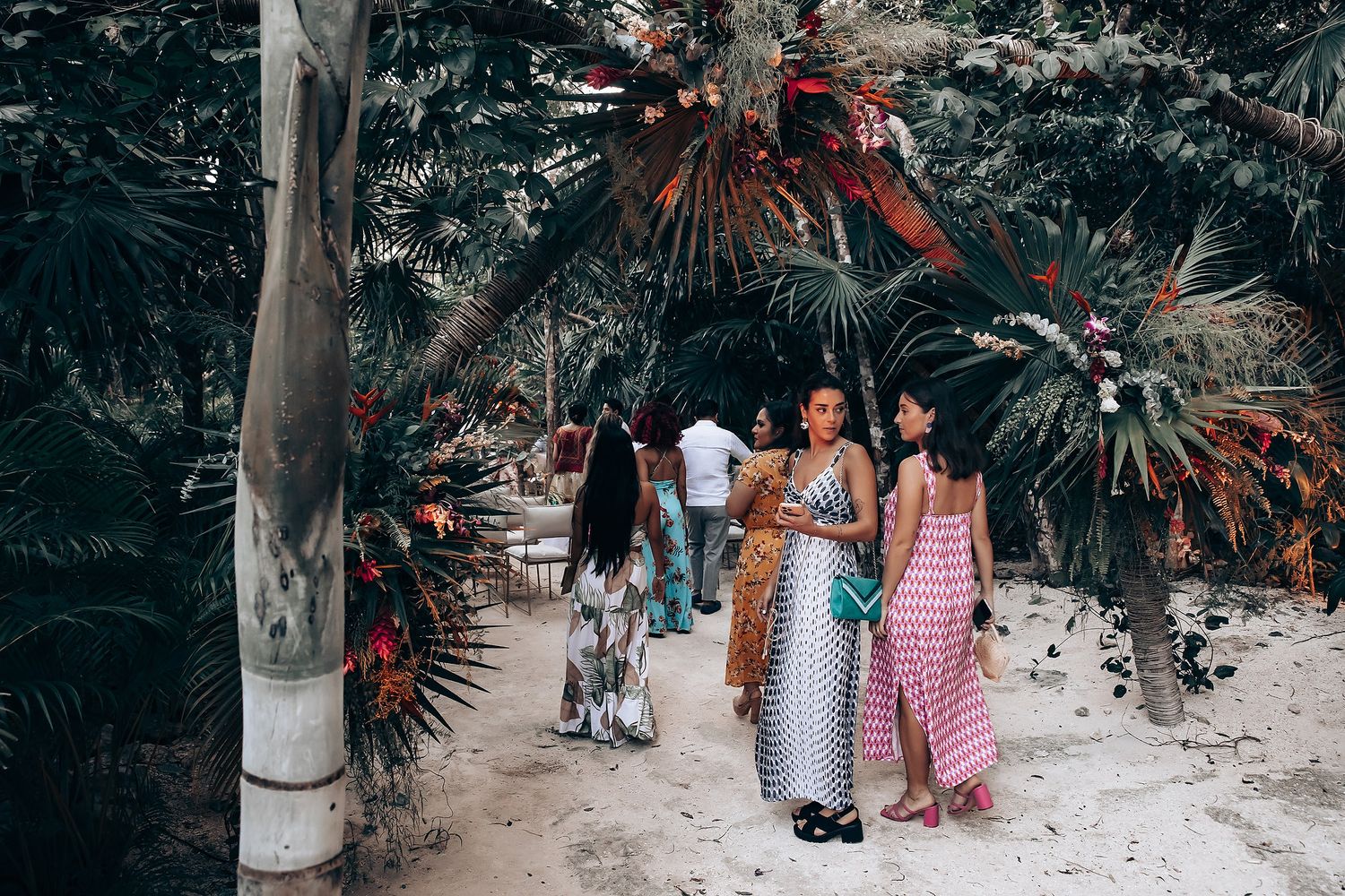 A group walks along a tropical palm-lined path during an outdoor celebration.