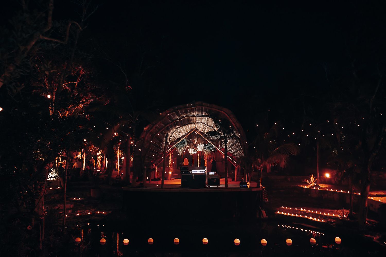Nighttime outdoor wedding venue illuminated with string lights and lanterns.