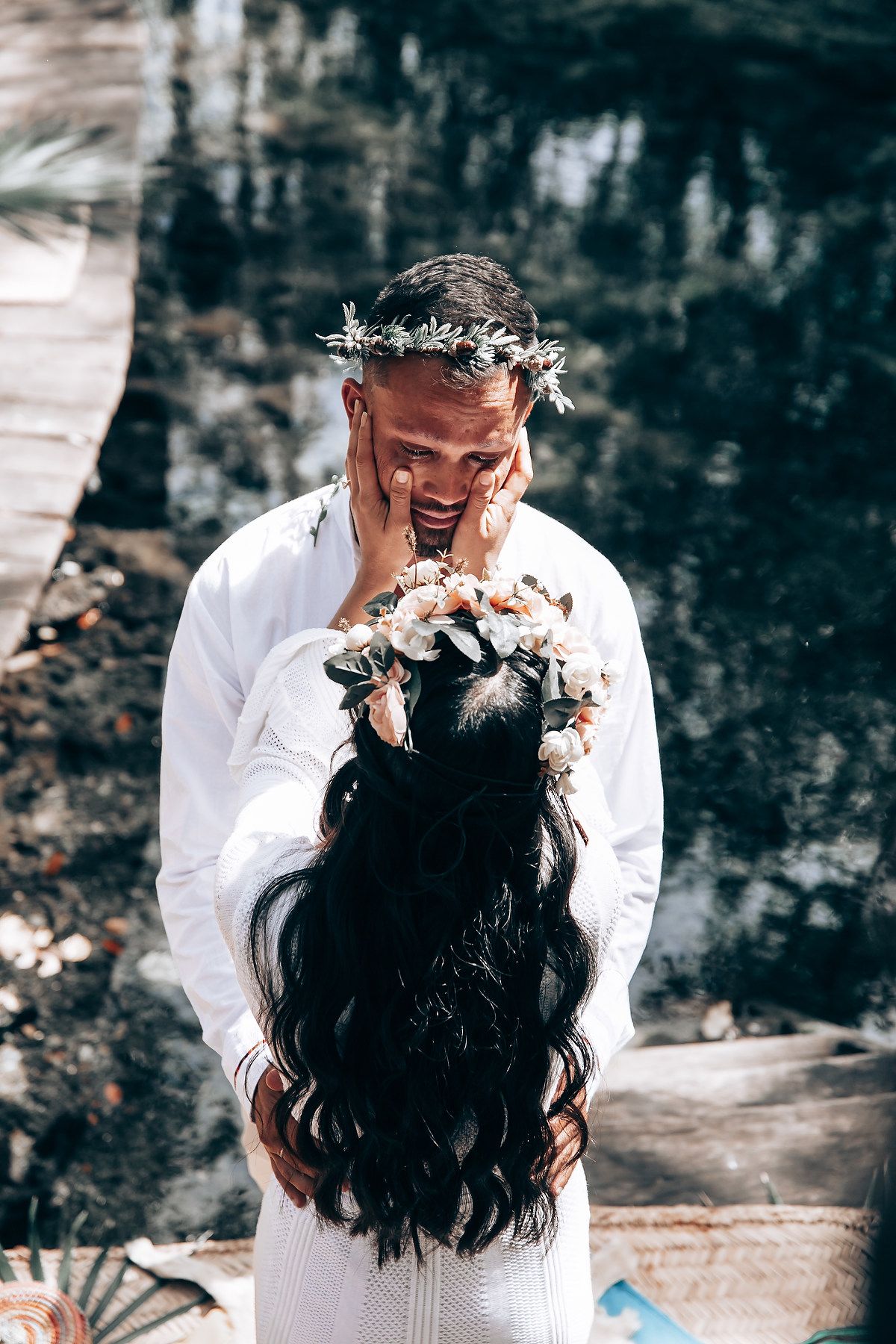 Intimate wedding moment captured between couple in white attire against dark background.