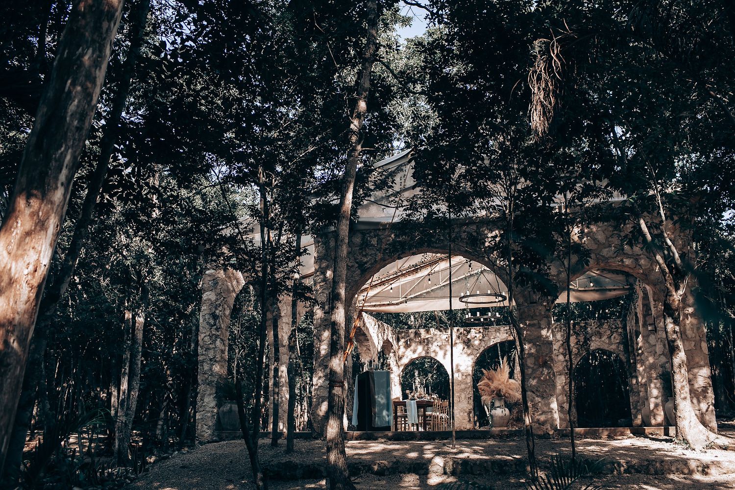 A romantic forest wedding ceremony setup with white chairs and natural decor in a wooded outdoor setting.