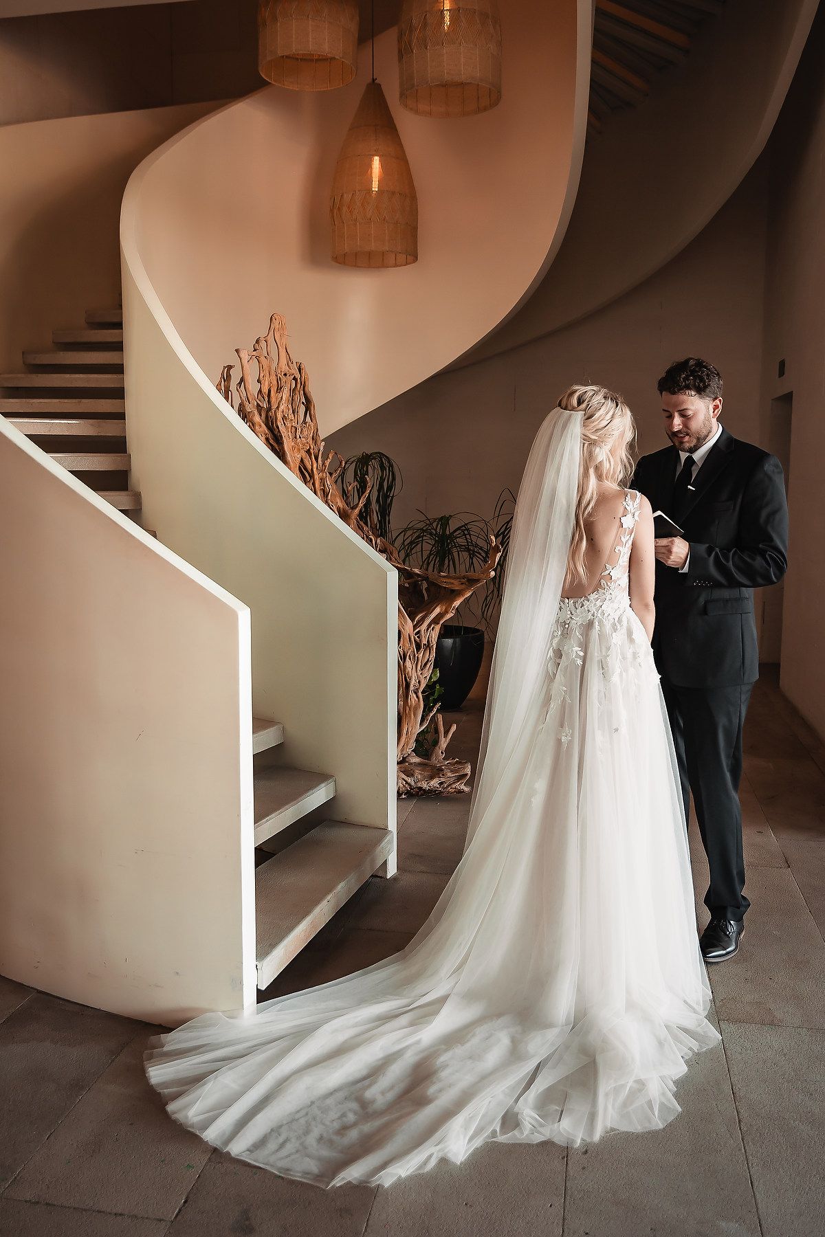 Elegant bridal portrait showing the dramatic train of a lace wedding gown against modern architecture.
