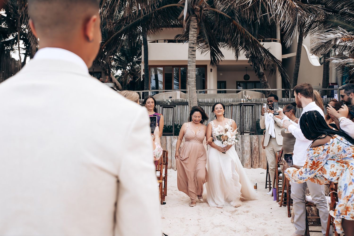 Wedding celebration outdoors with guests in coordinated pink and white attire.
