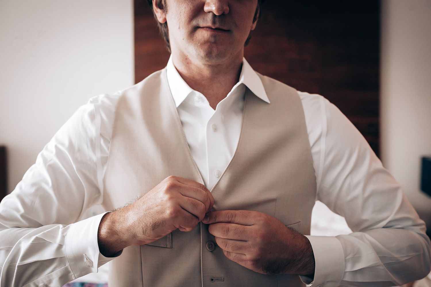 Close-up sequence showing someone adjusting and buttoning a white dress shirt.