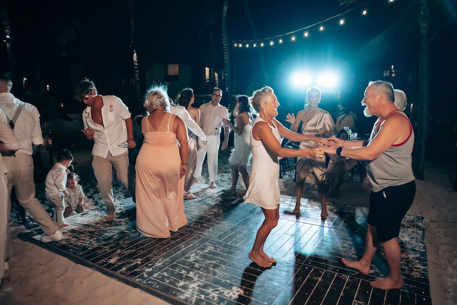 Evening wedding reception with string lights and dancing guests.