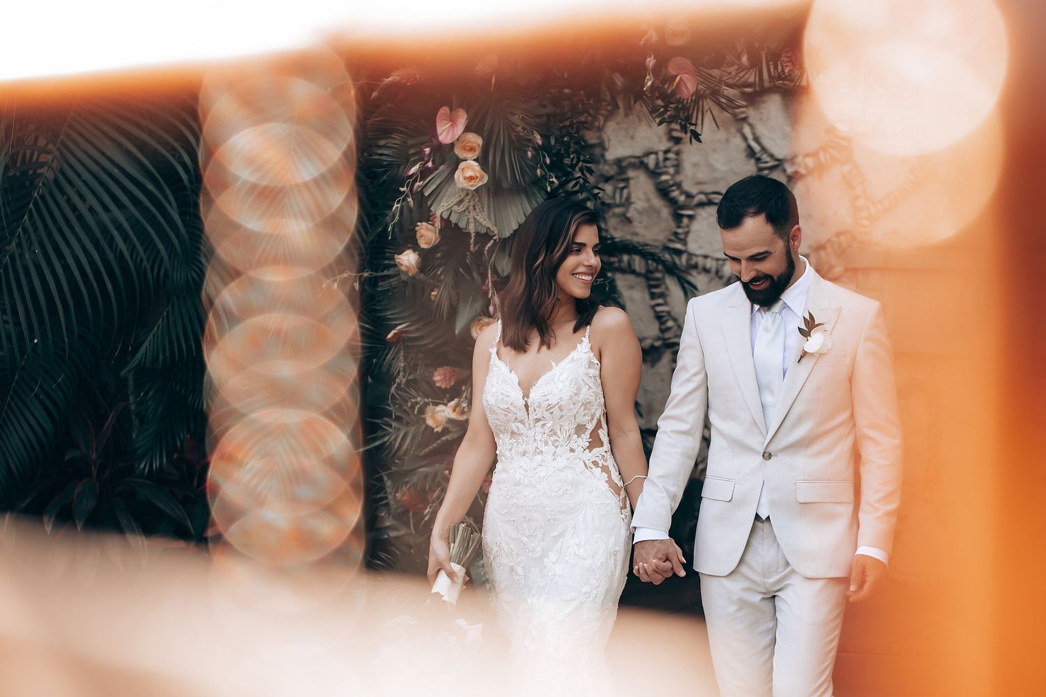 Romantic wedding scene with soft orange lighting and tropical palm trees in the background.
