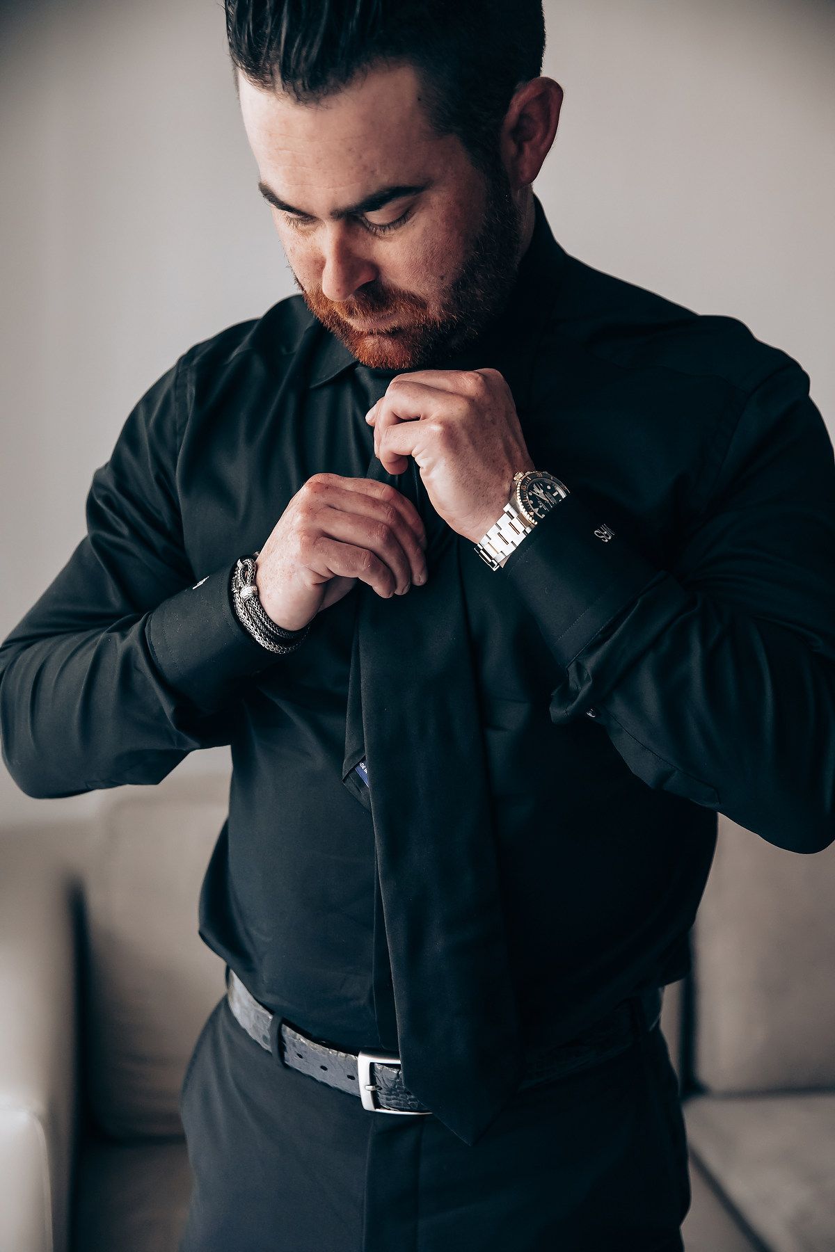 Series of shots showing someone in black formal wear adjusting their collar and cuffs.