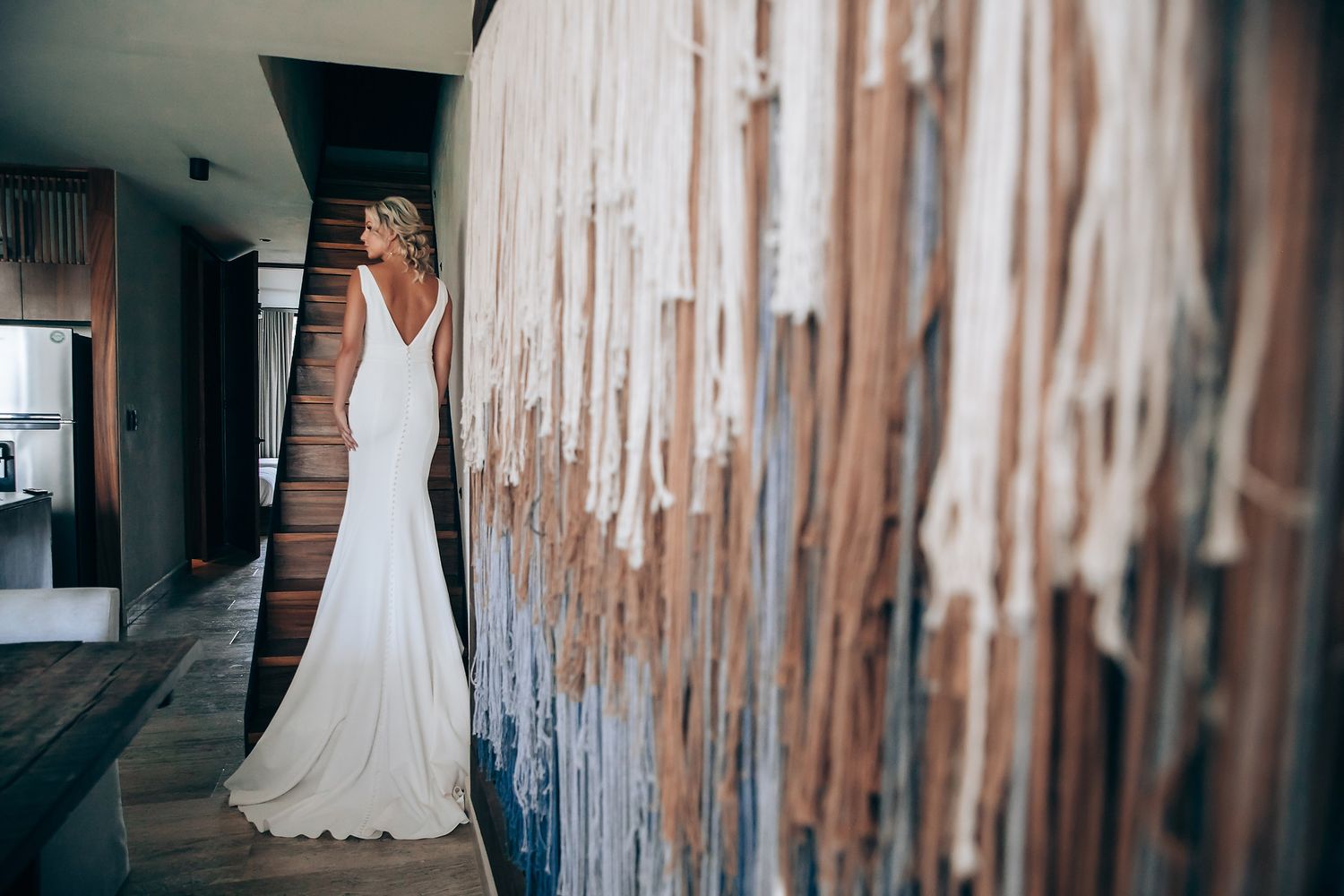 White wedding dresses displayed against a rustic wooden wall backdrop.