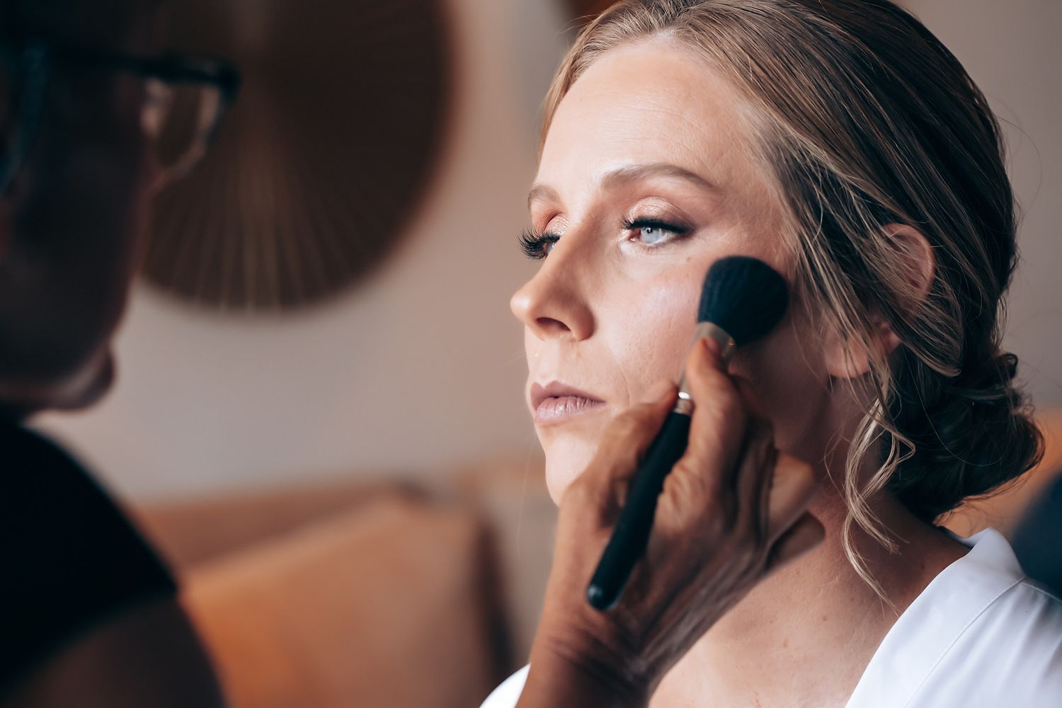 A woman having her makeup applied by a professional makeup artist.