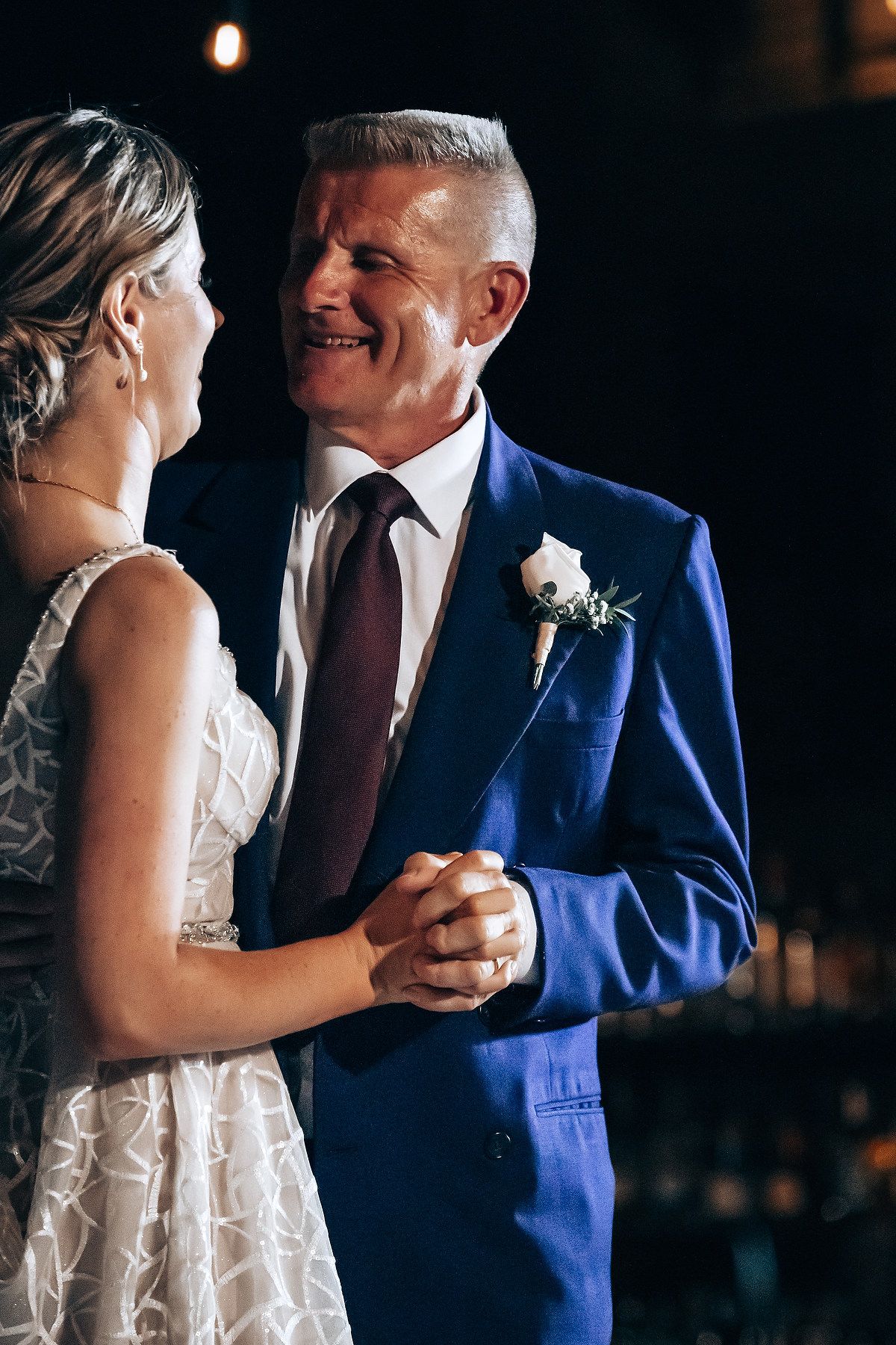 A bride and groom embrace and smile at each other during their wedding reception.