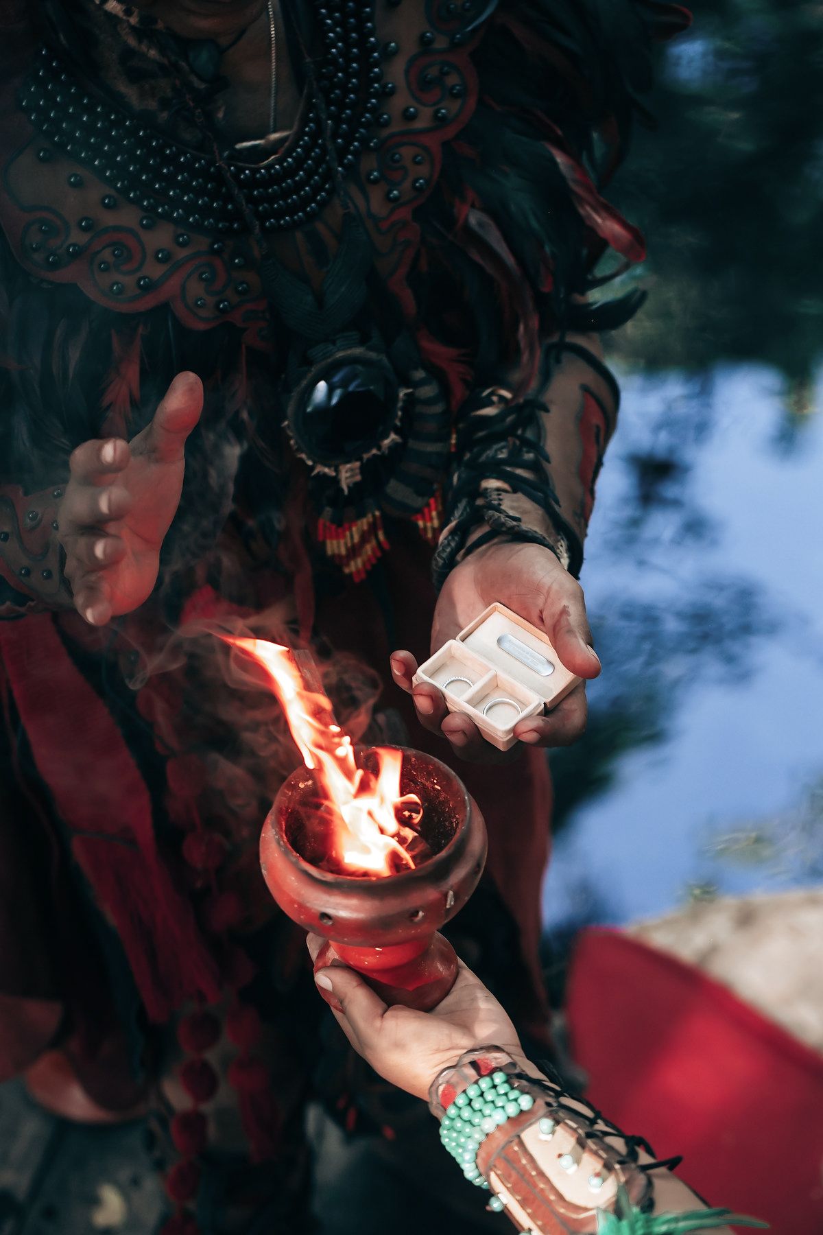 A person holds a ceremonial object in their hands, surrounded by intricate decorations.