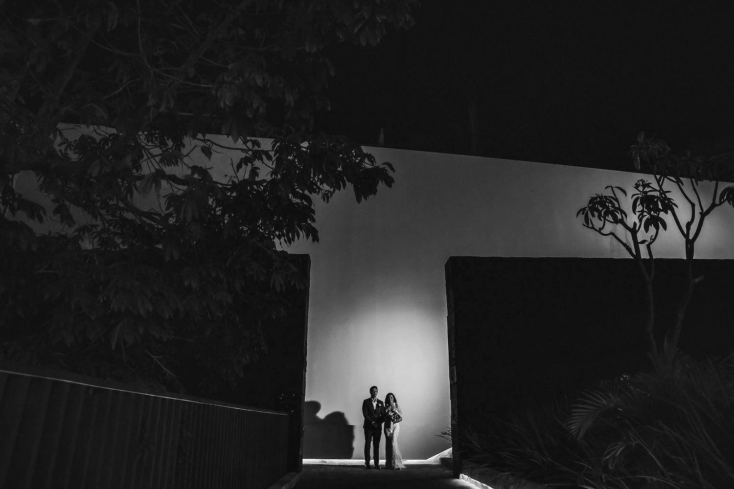 Dramatic black and white architectural wedding portrait with backlighting.
