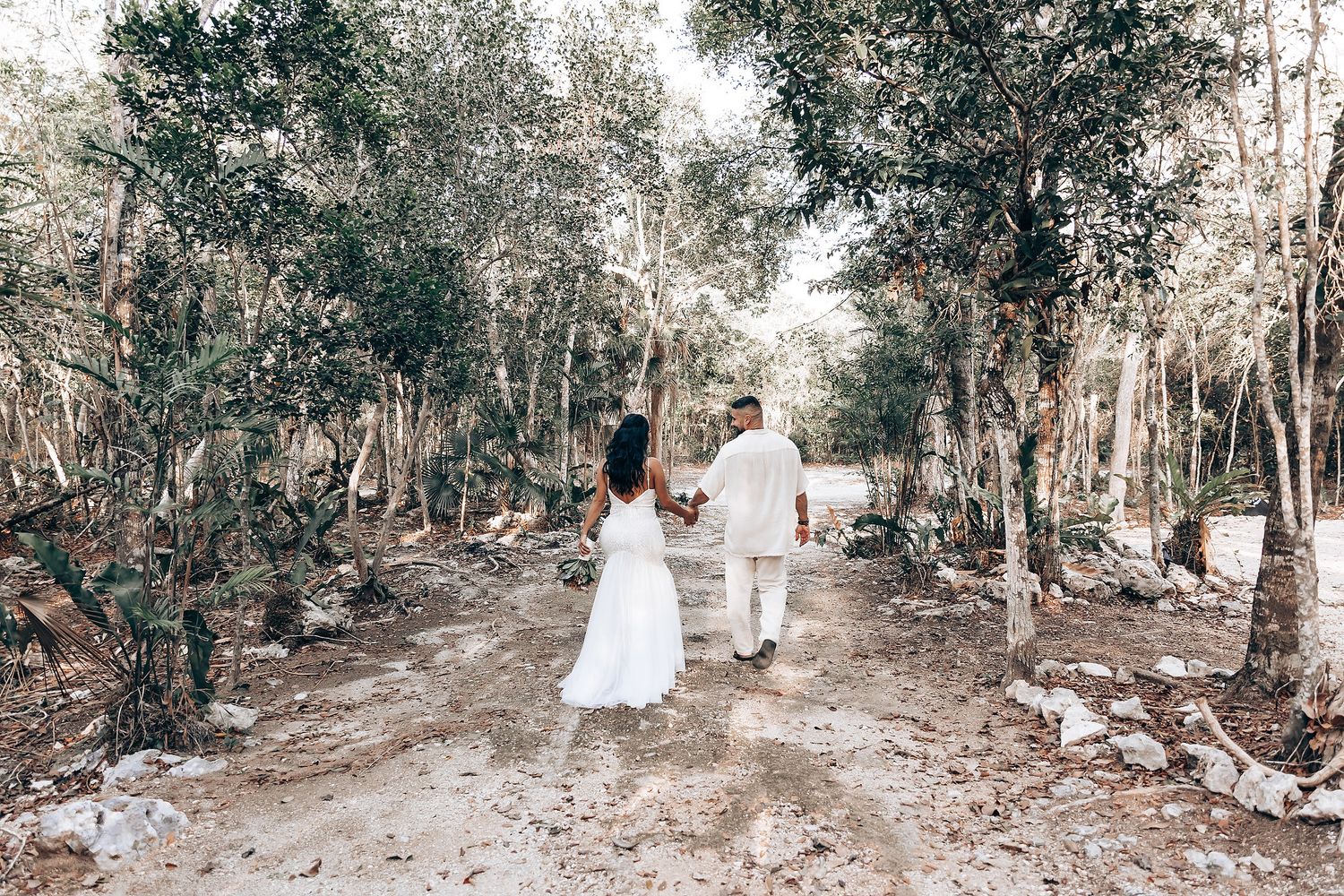 Couple walks through forest path after traditional ceremony.