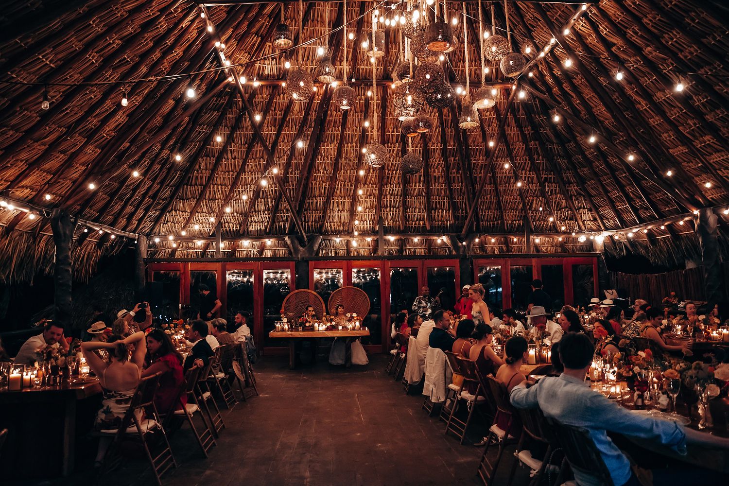 Reception venue with string lights hanging from wooden beams creating a warm ambiance.
