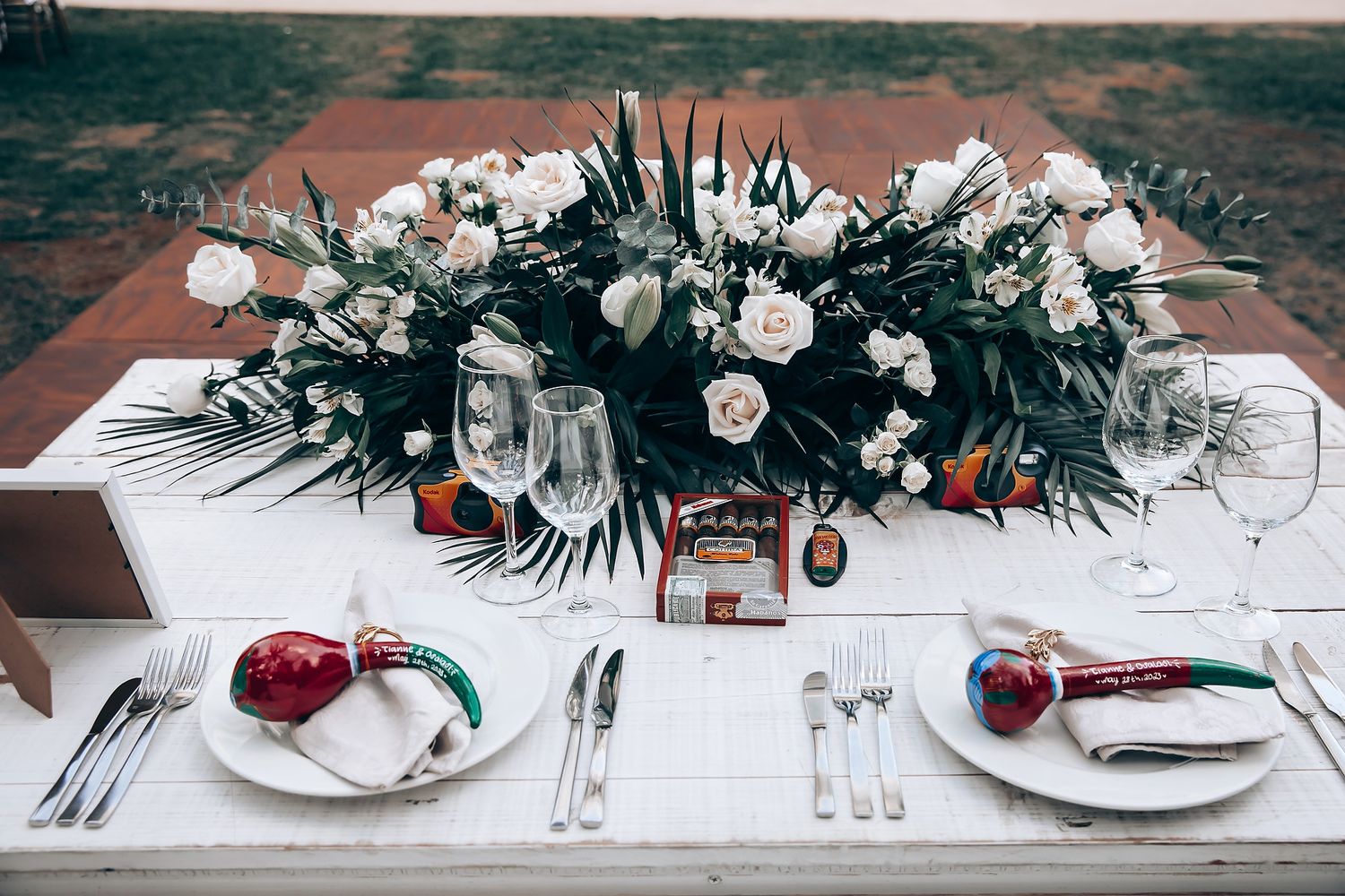 Elegant white floral table decorations and place settings at a wedding reception.