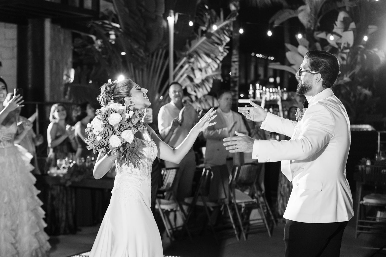 Bride and groom share a joyful moment on the dance floor at their outdoor wedding reception at night.