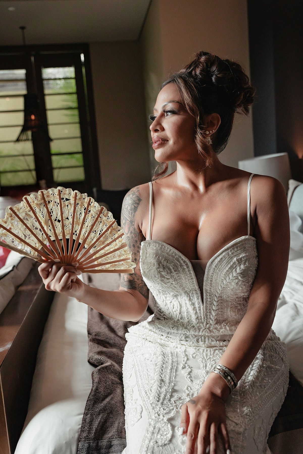 Close-up shots of a bride in a beaded wedding dress posing with a decorative fan.