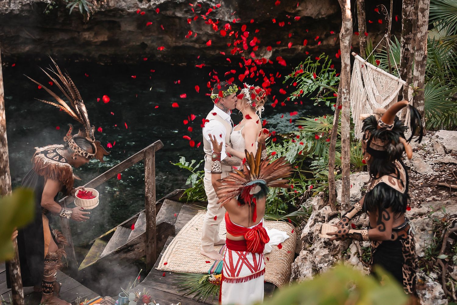 Red flower petals scatter through the air during an outdoor celebration.