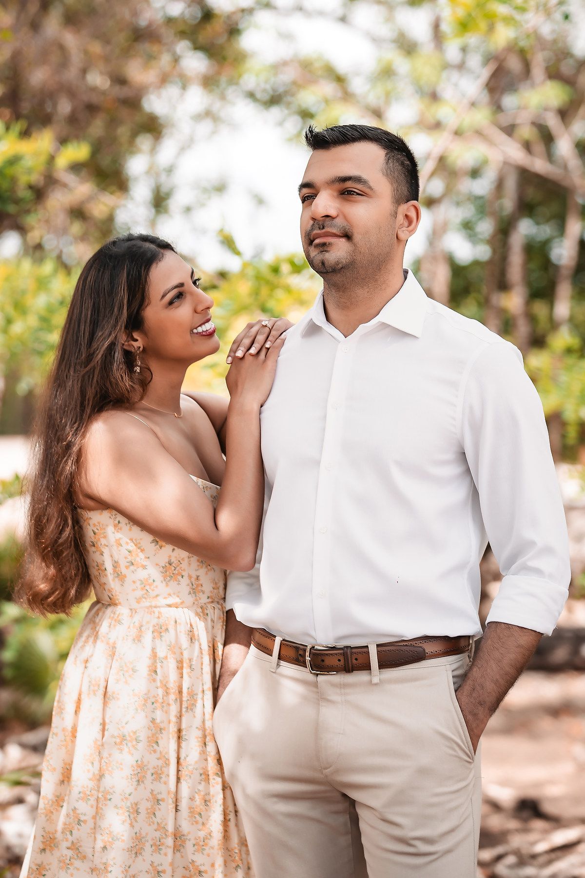 Playful couple shares intimate moments during outdoor photoshoot in natural setting.