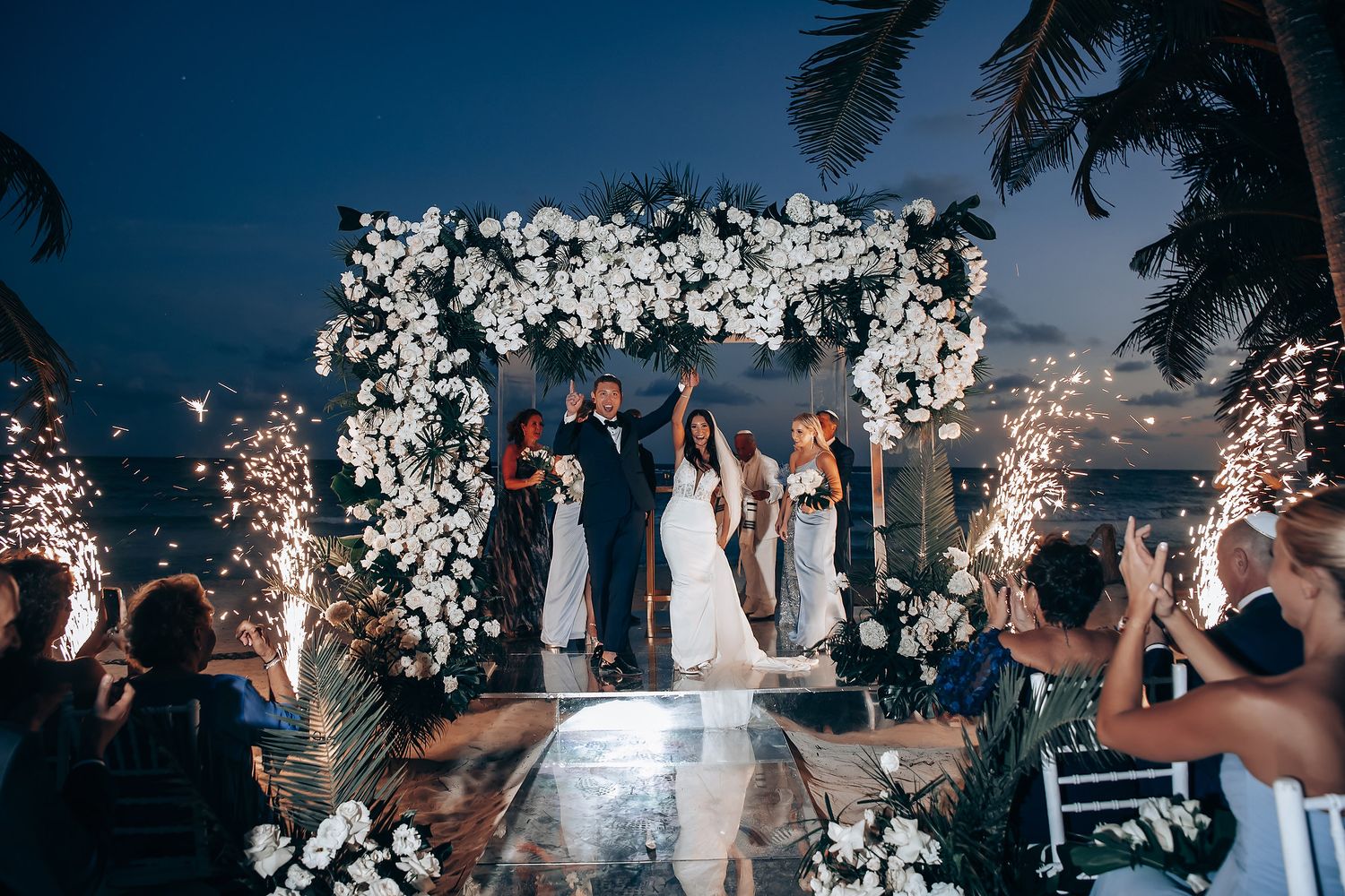 Evening wedding reception with illuminated decor and dancing under the night sky.
