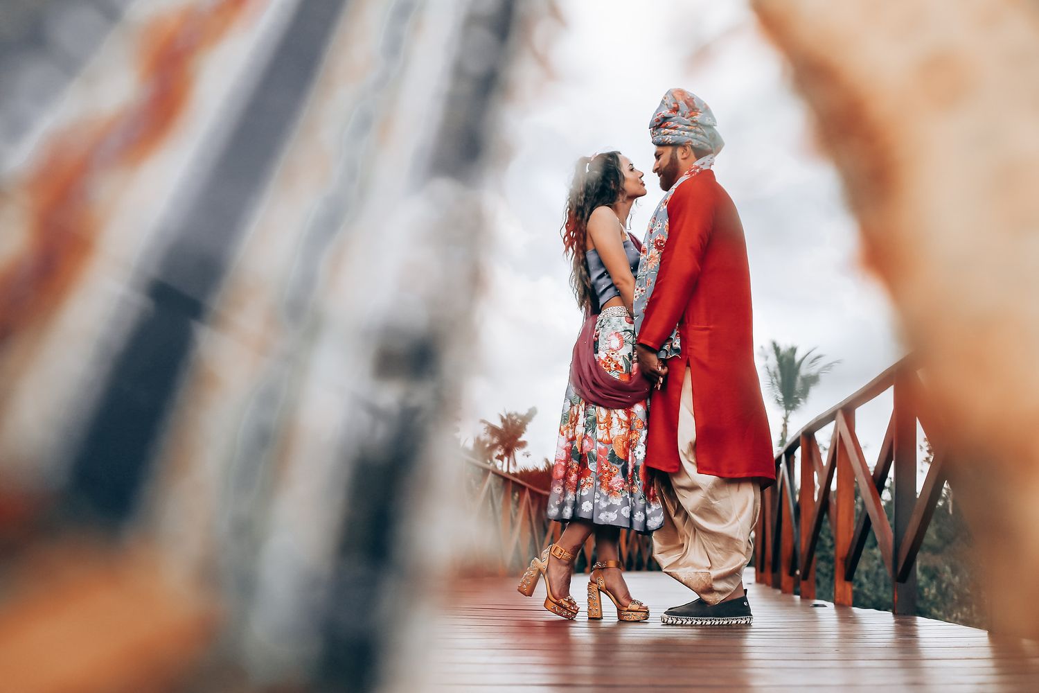 A couple in formal attire dances elegantly on a wooden floor, with the woman wearing a floral dress and man in red jacket.