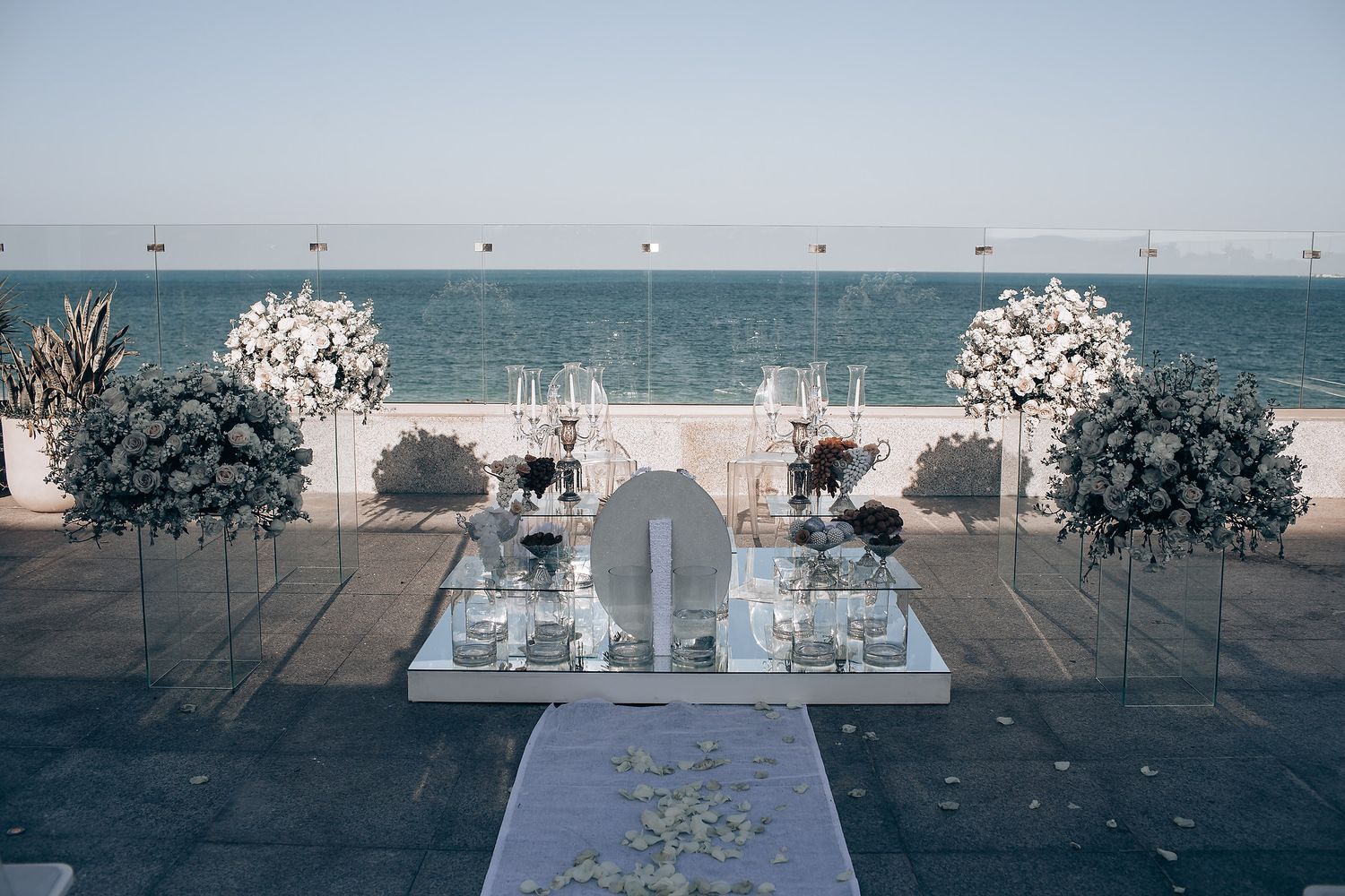 Elegant beachfront wedding ceremony setup with white floral arrangements and ocean views.