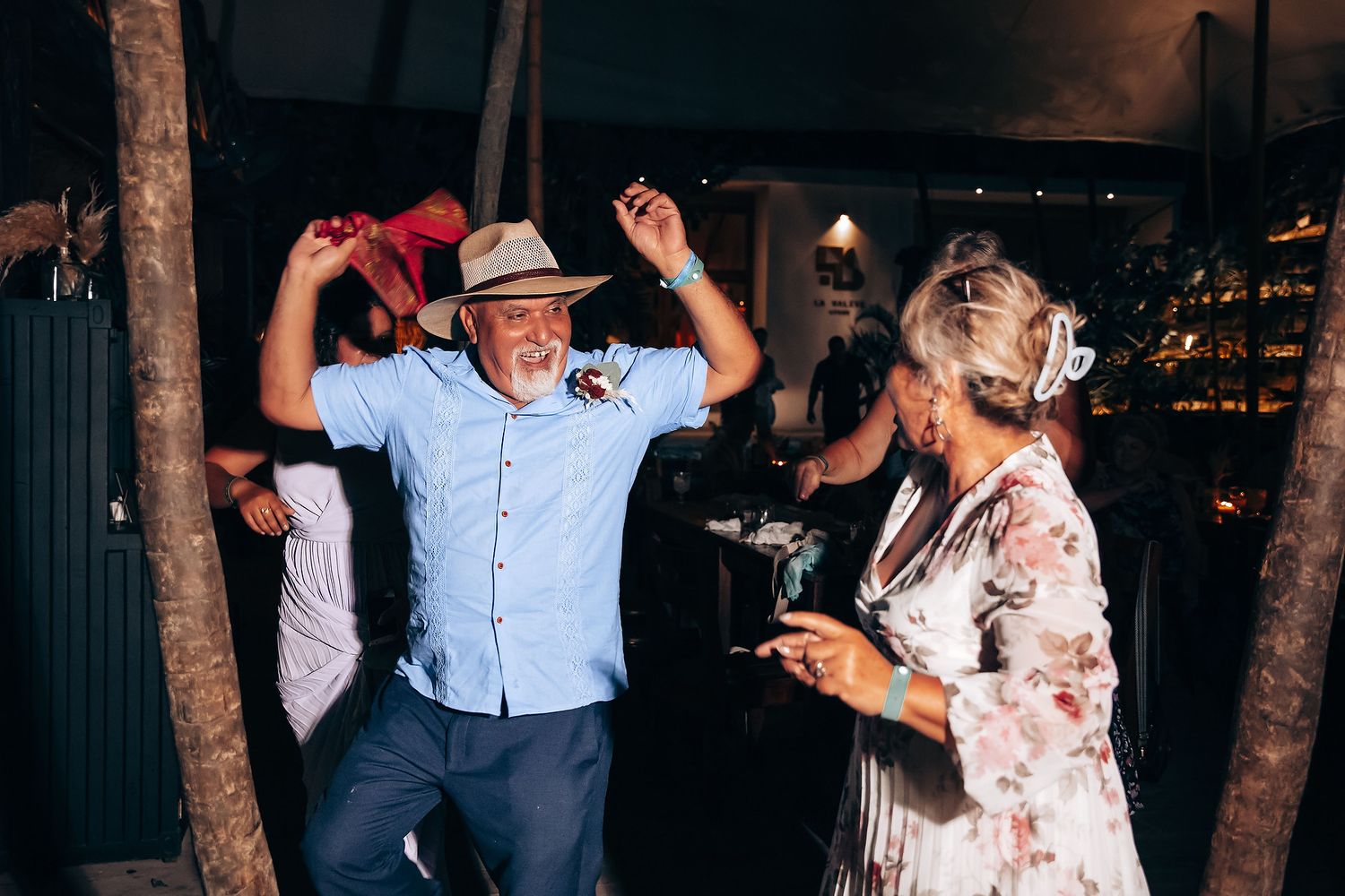 Party guests dance and socialize beneath string lights at an outdoor evening celebration.