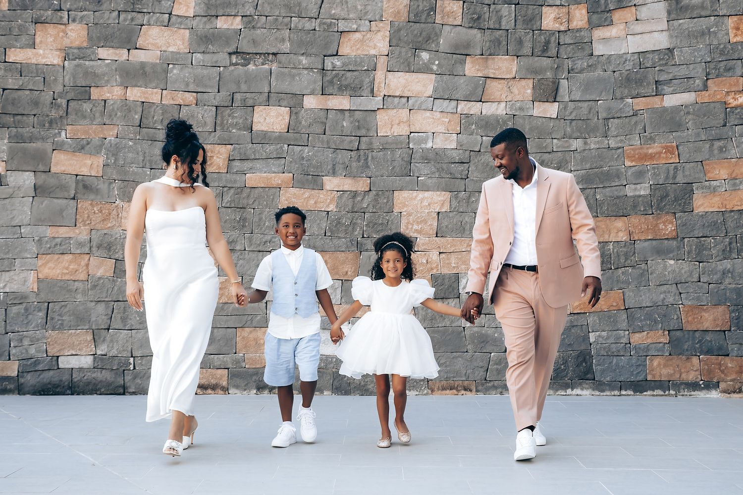 A group walking together in formal attire against a stone wall backdrop.