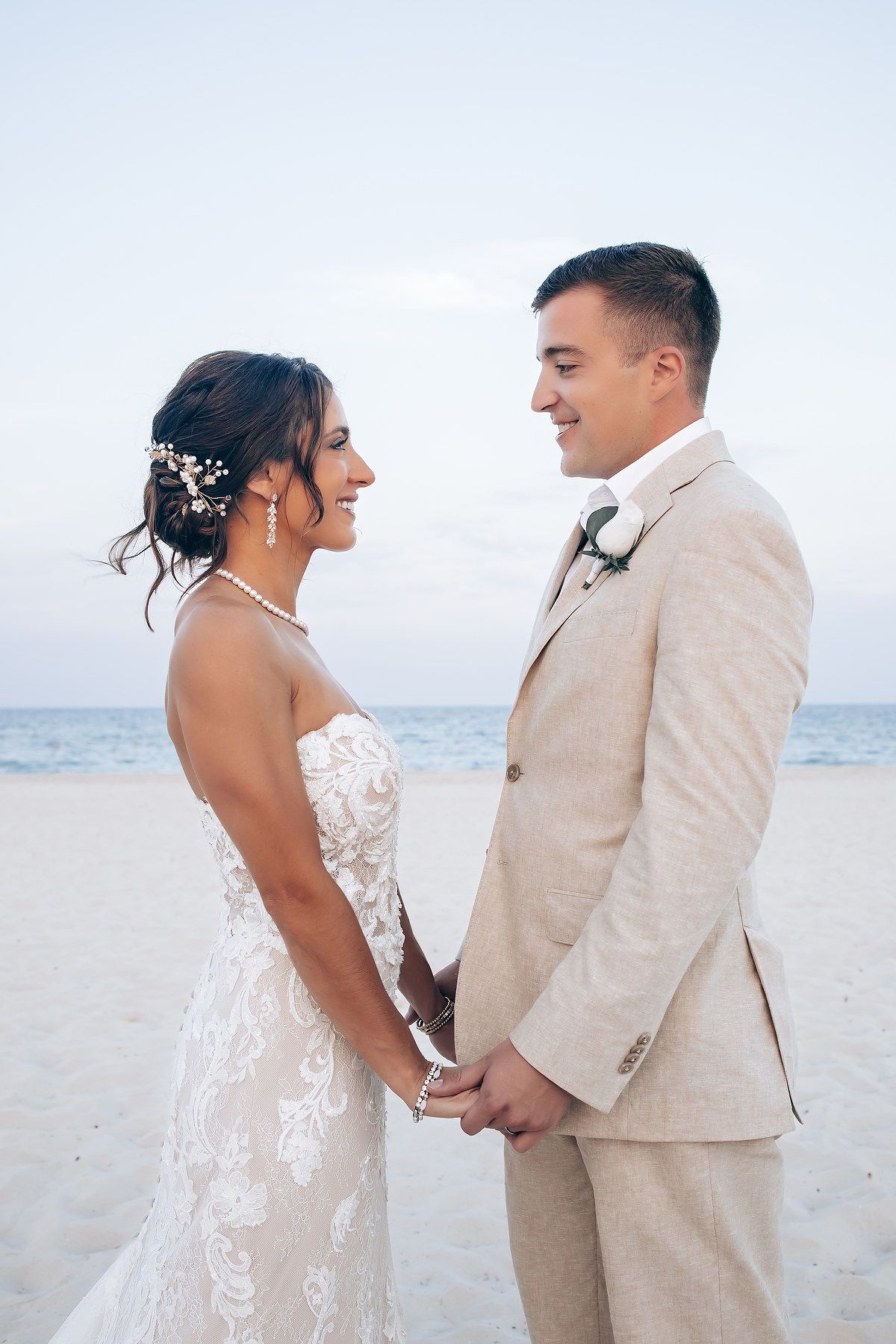 Romantic beach wedding portraits with couple in beige and white attire against ocean backdrop.