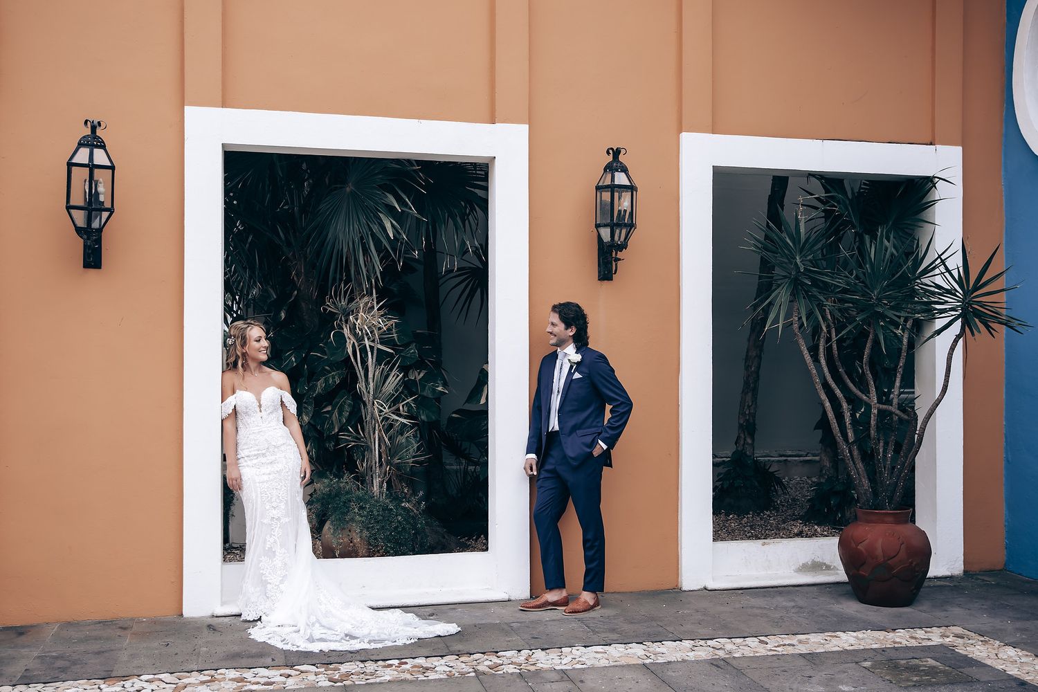Wedding photo shoot against a peach-colored wall with decorative lanterns and cacti.