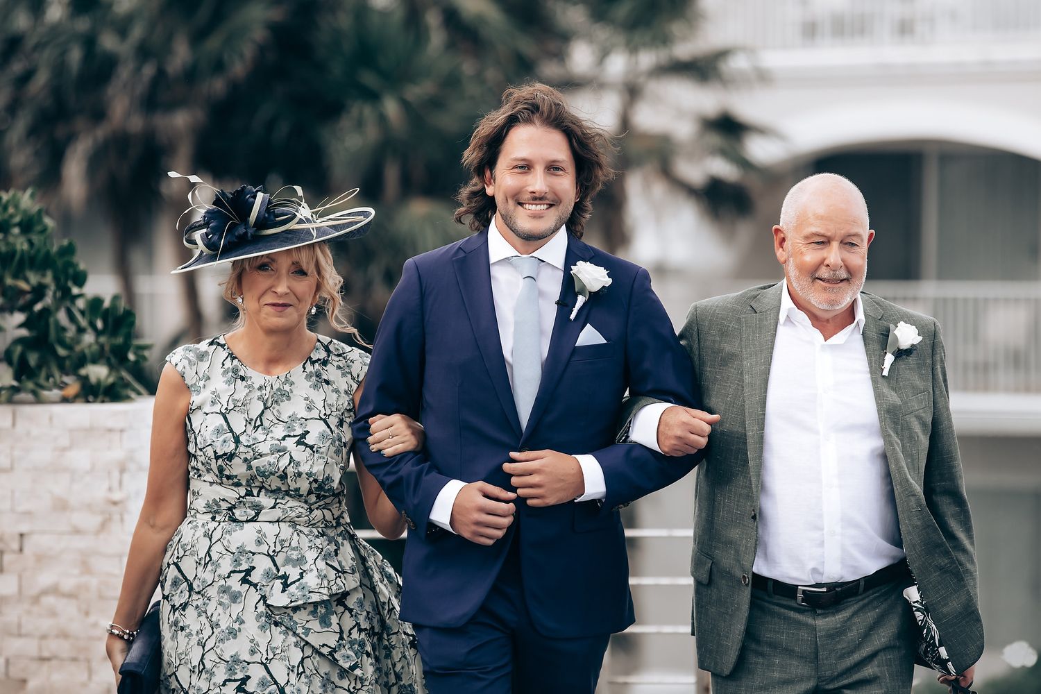 Wedding party members walk together outdoors in formal attire.