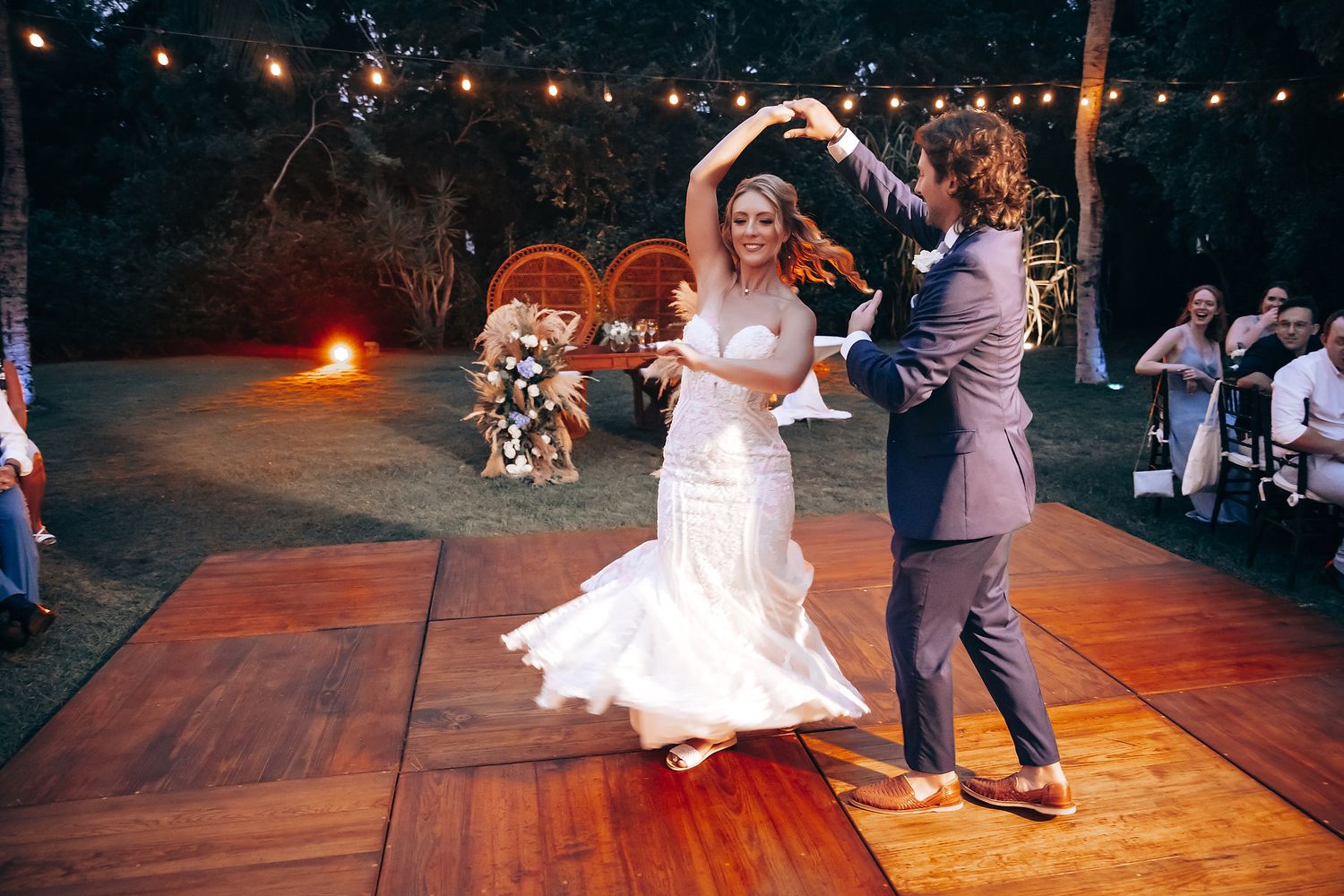 Romantic first dance on an illuminated outdoor dance floor with string lights overhead.
