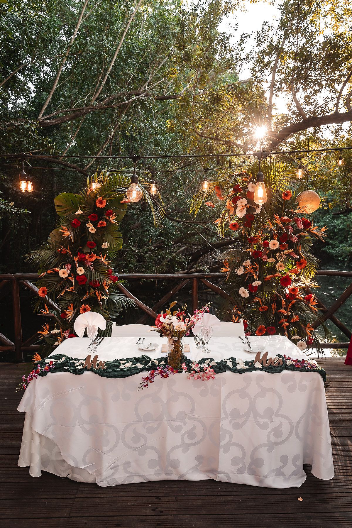 Elegant wedding reception table decorated with white tablecloth and floral accents under string lights in a garden setting.
